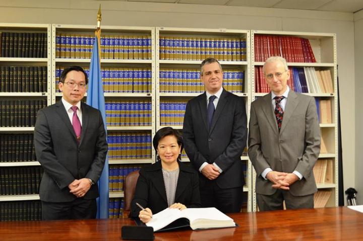 The Permanent Representative of Singapore to the United Nations, Ms Karen Tan (seated), signing the Arms Trade Treaty at the UN Office of Legal Affairs.