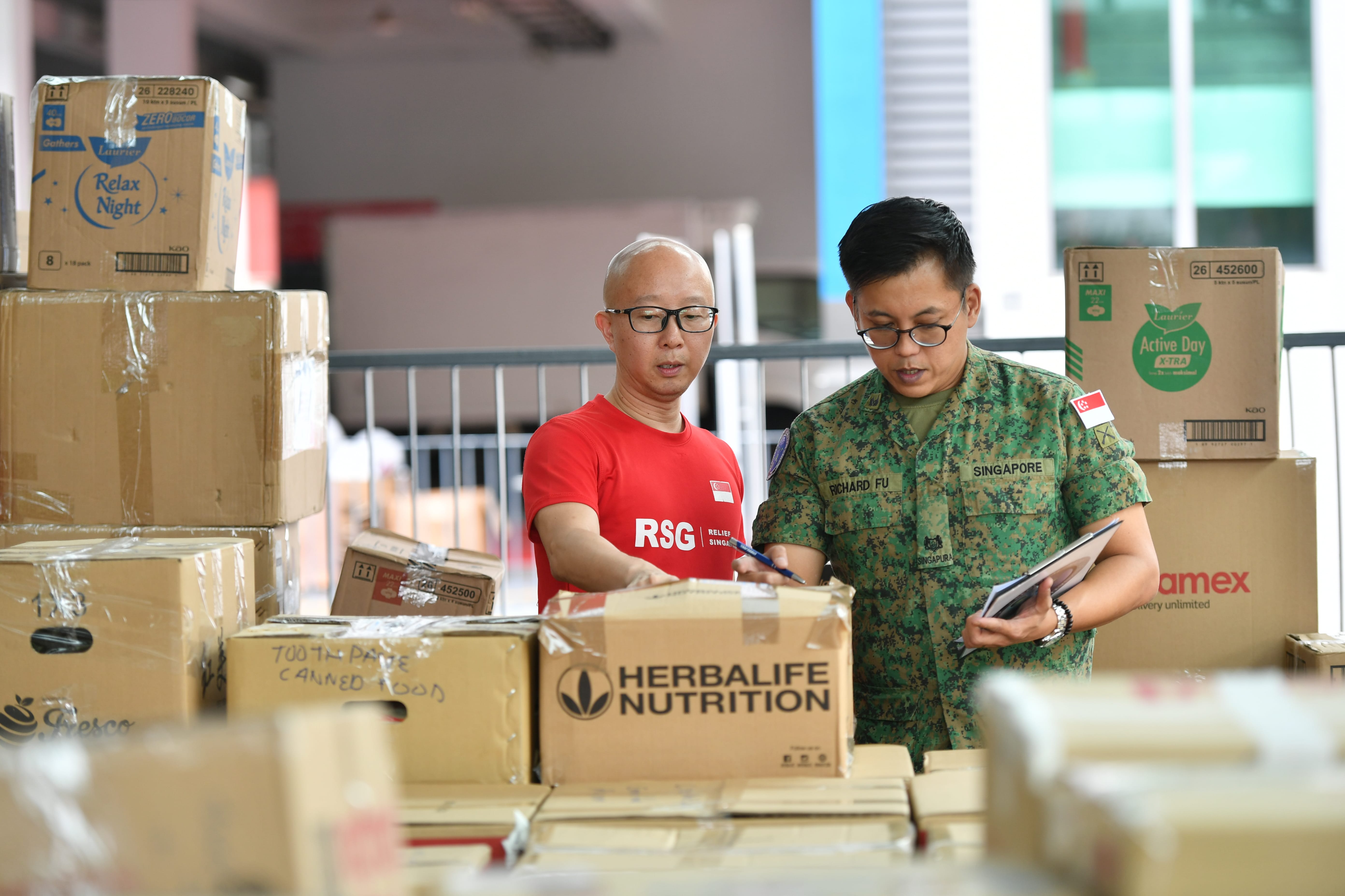 SAF’s RHCC personnel & Relief Singapore rep reviewing humanitarian aid supplies.