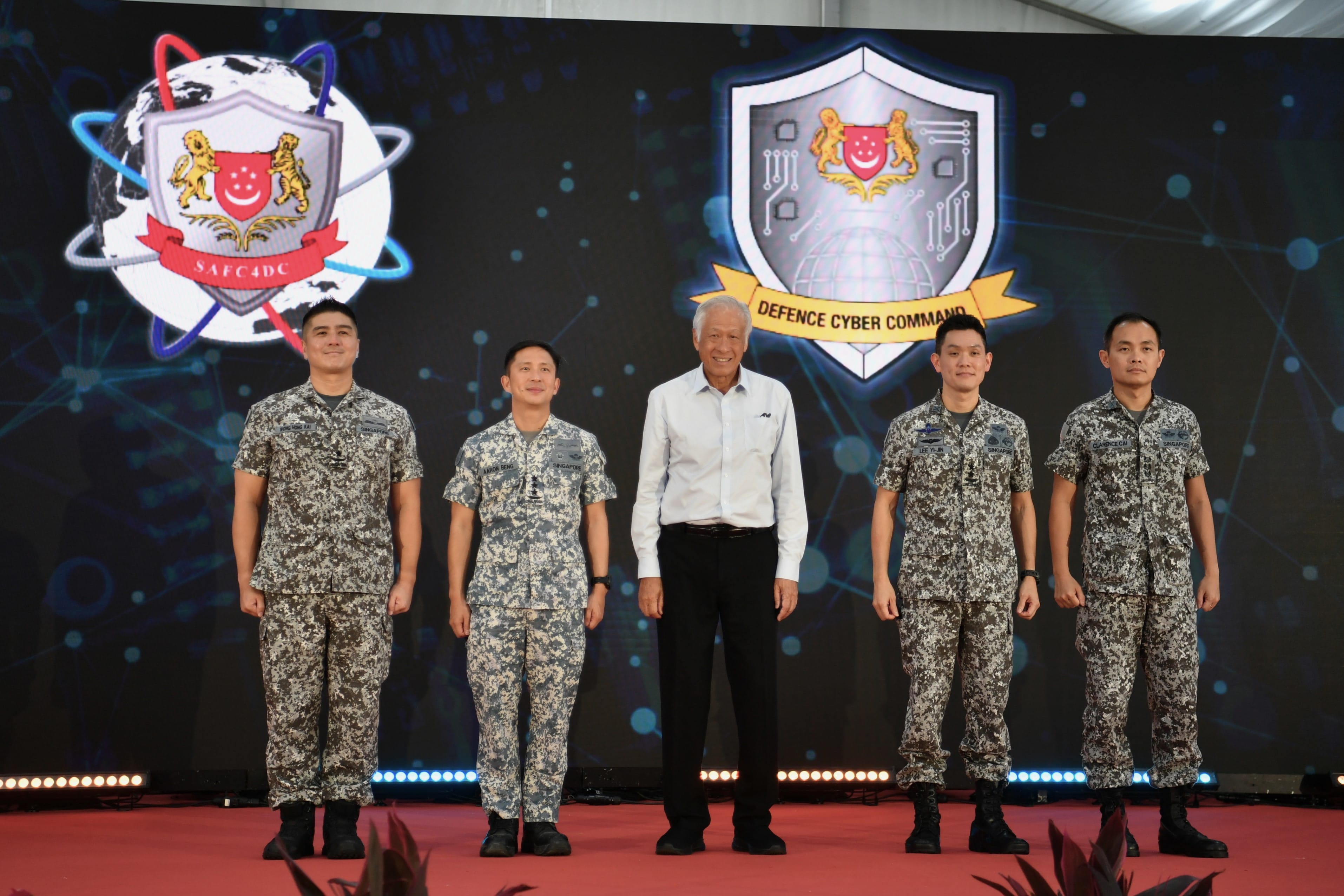 Five people pose onstage before SAFC4DC and Defence Cyber Command logos. Four wear camo uniforms.