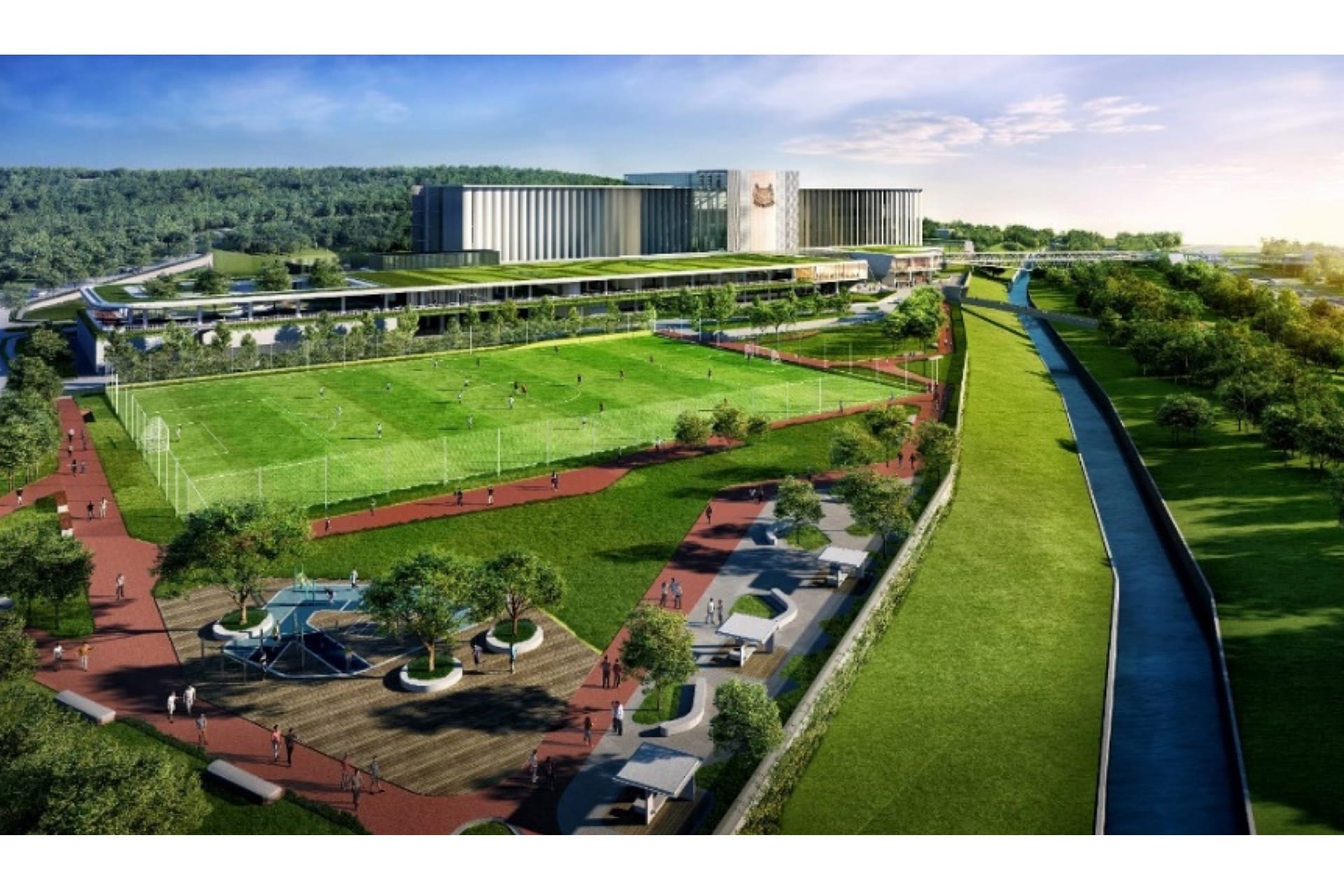 Aerial view of school grounds with a sports field, walking path, and a waterway.