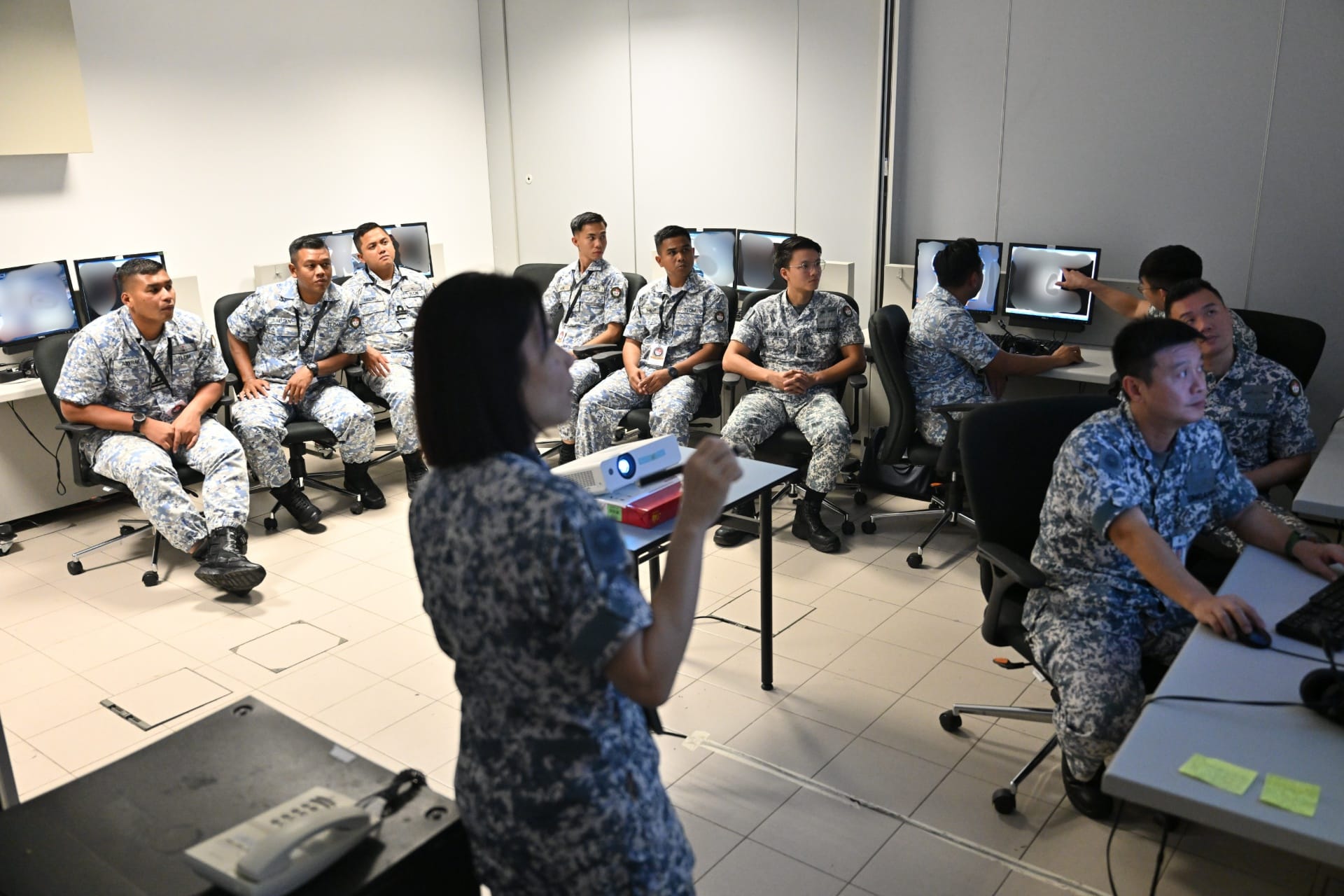 RSN personnel briefing RMN personnel during the pre-planning phase of the Naval Tactical Trainer (NTT) warfare simulations.