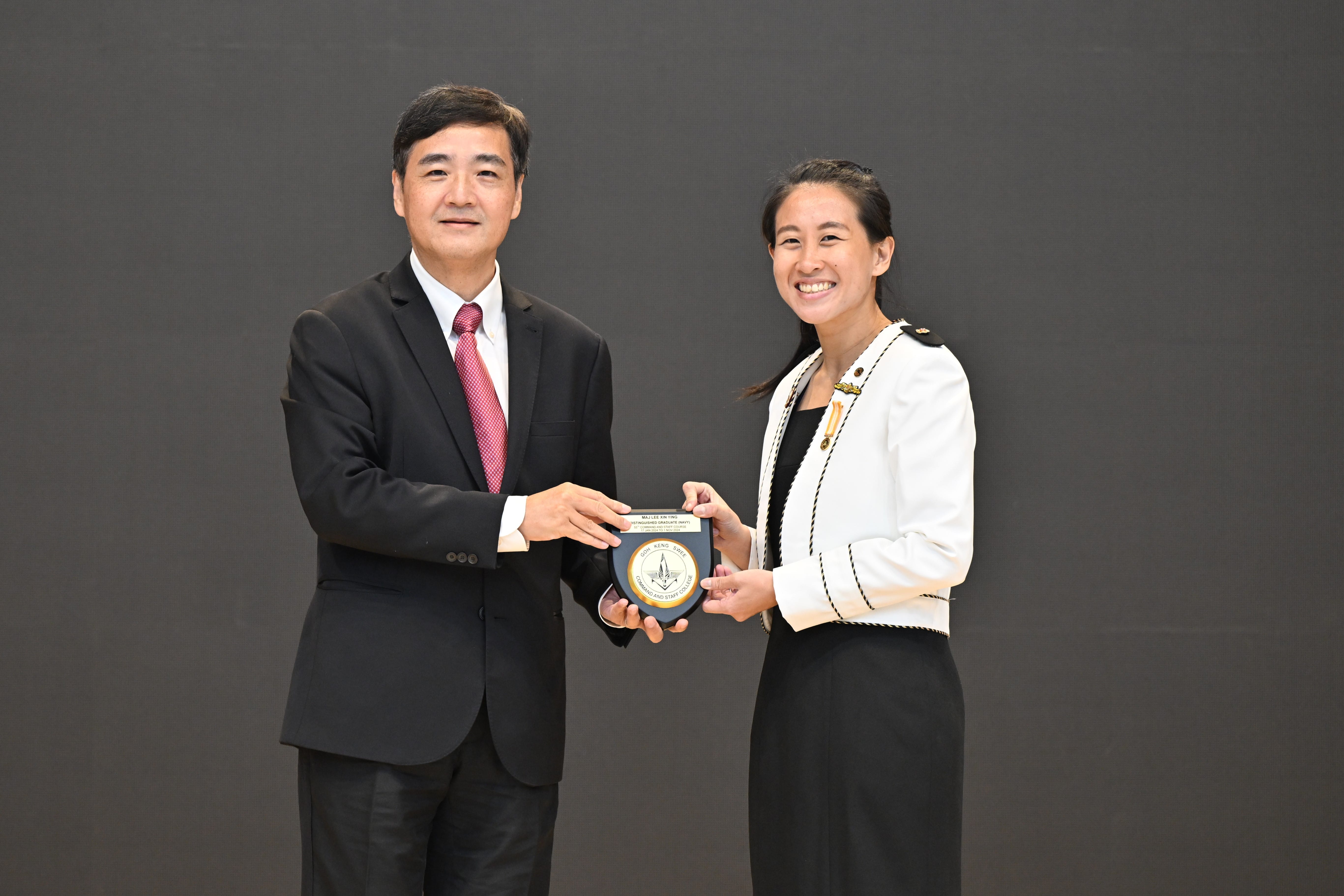 Mr Heng presenting the graduation plaque to MAJ Lee Xin Ying.