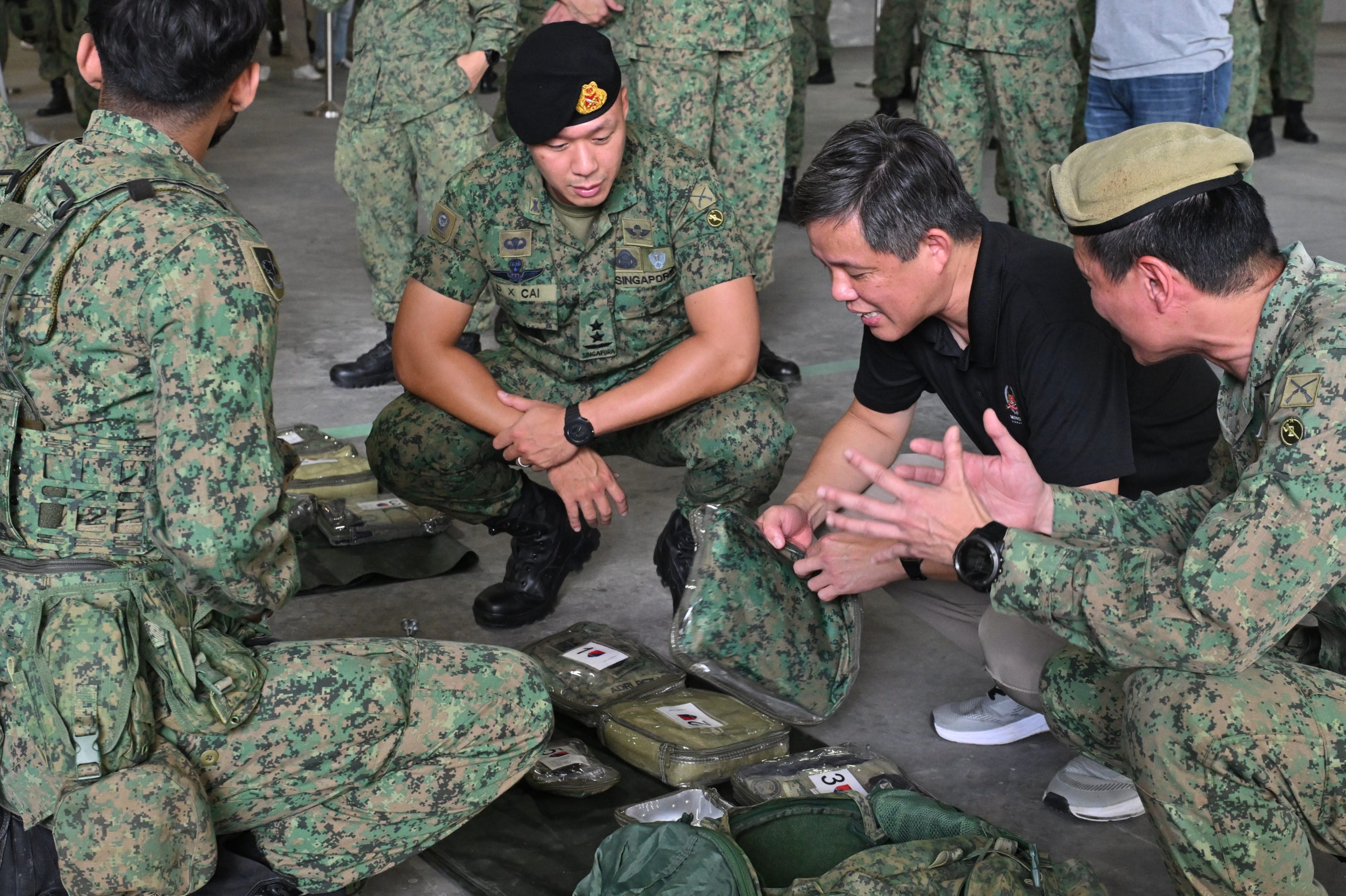 Soldiers in camouflage uniforms inspect military pouches.
