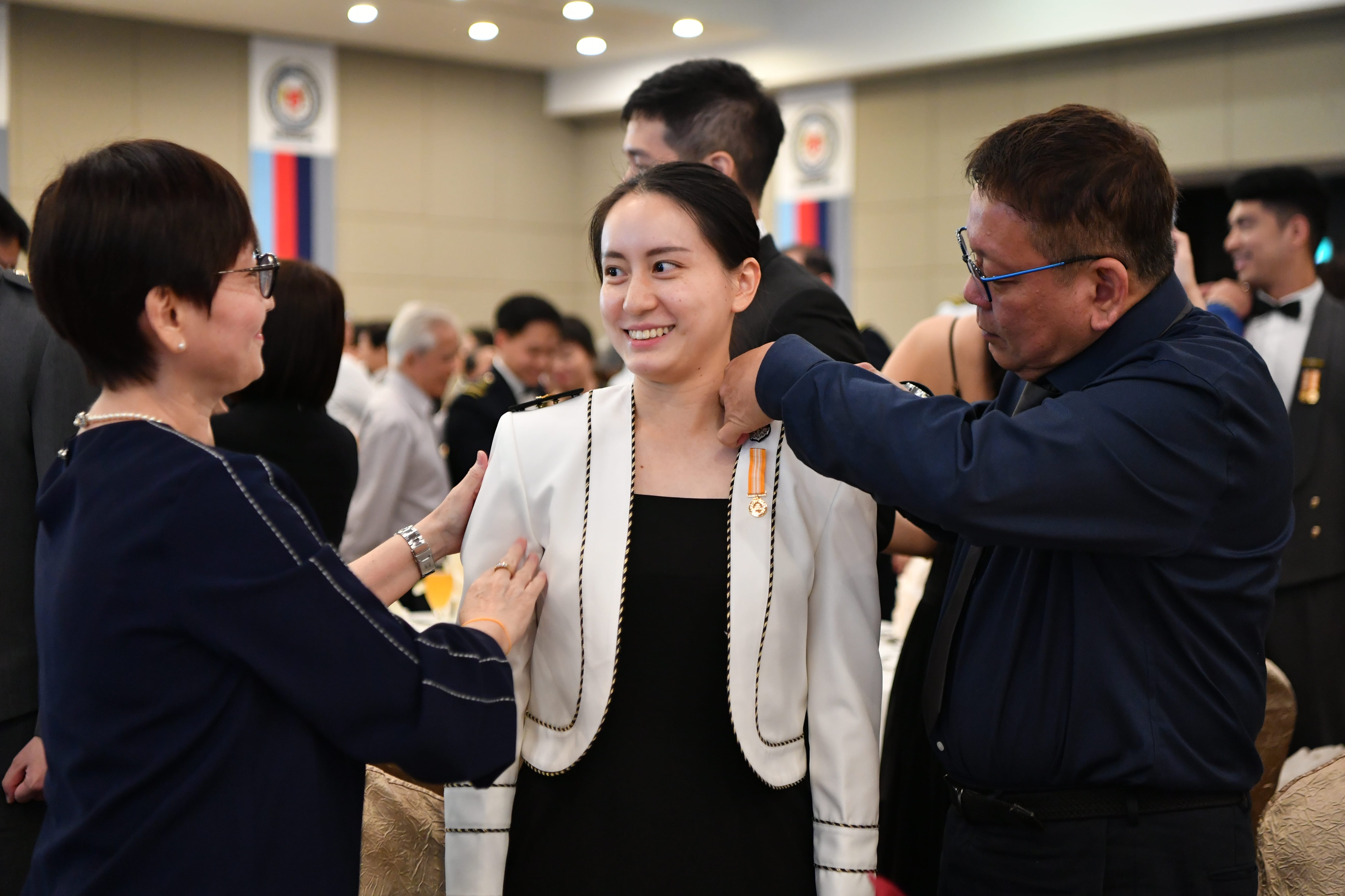 Family of ME4 Fion Lim Jia Hui, a Naval Engineer from the Republic of Singapore Navy, affixing her new rank epaulettes on her.