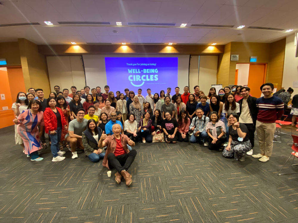 Large group photo taken after a Well-being Circles session in front of a projection screen