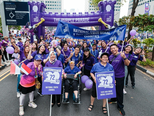 Group at The Purple Parade holding banners and posing with a wheelchair participant