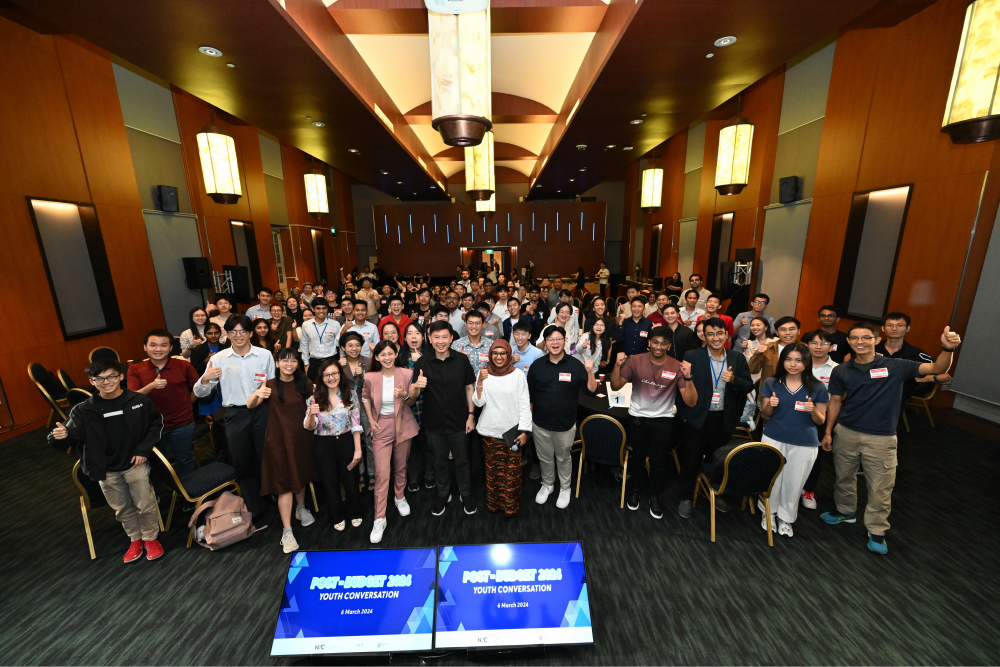 Large group poses with thumbs up in a hall