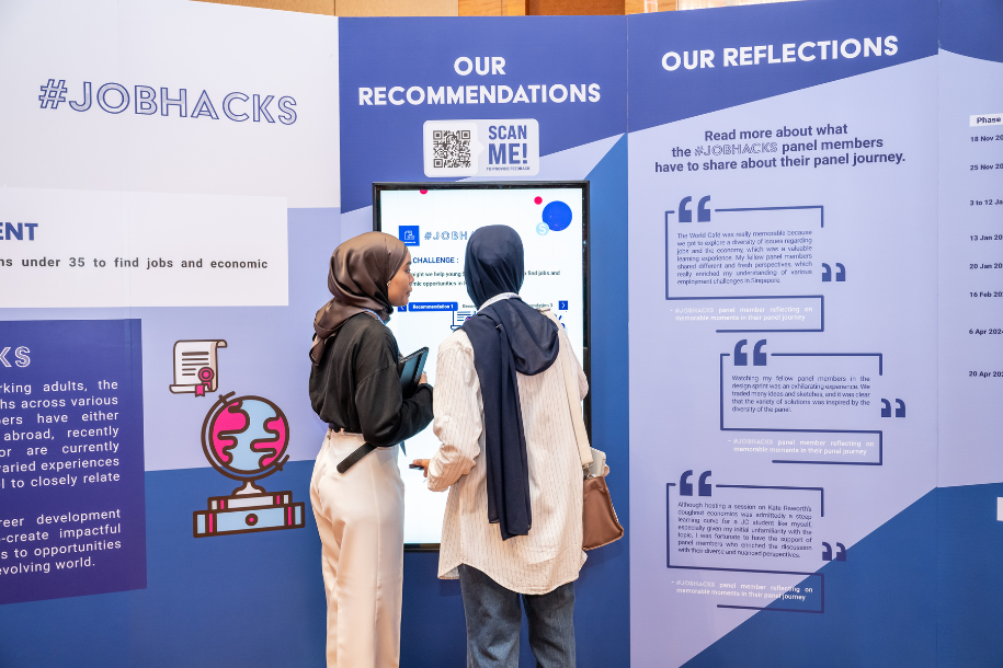 Two ladies interacting with a screen at one of the booths.
