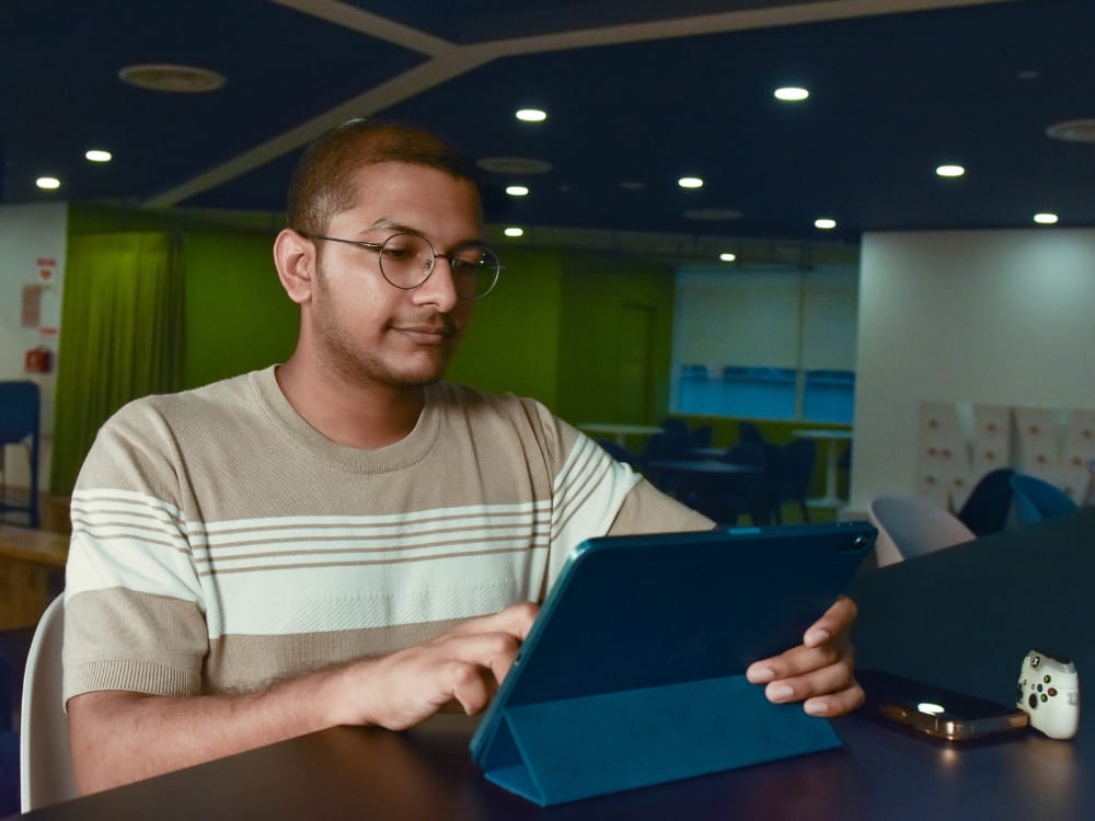 Shafeek using a tablet at a counter in a dimly lit indoor space