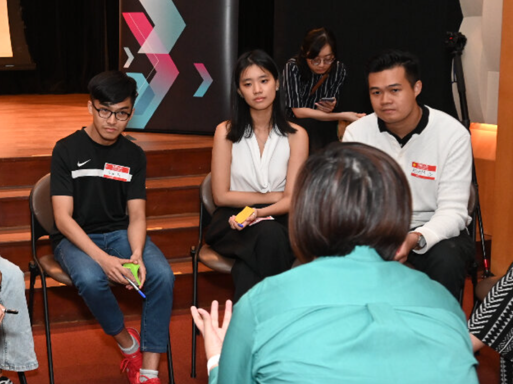 Three youths listening to a facilitator during a small group discussion at a youth panel session