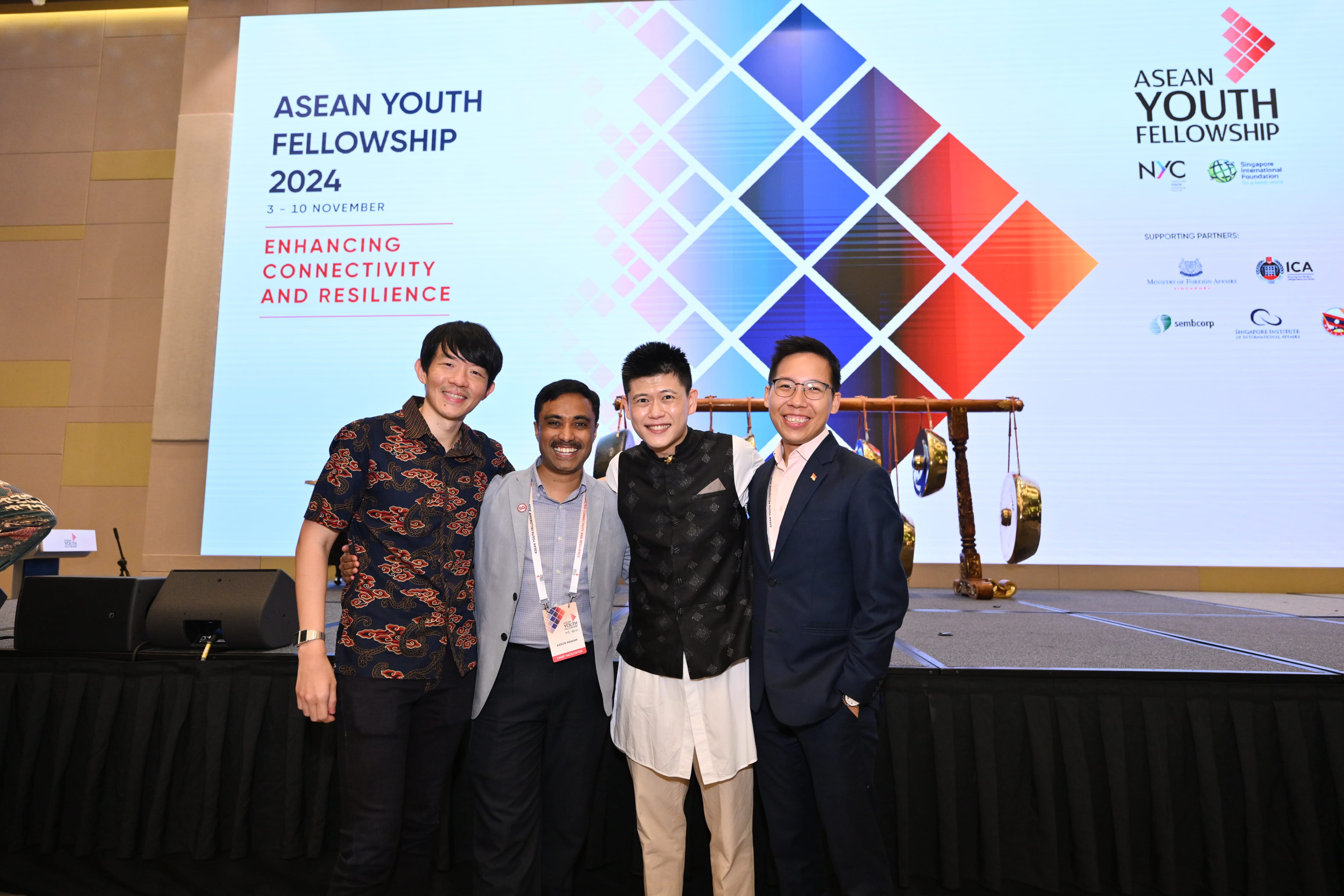 Group of men posing for a photo in front of a stage, with "ASEAN Youth Fellowship 2024" projected on the stage.