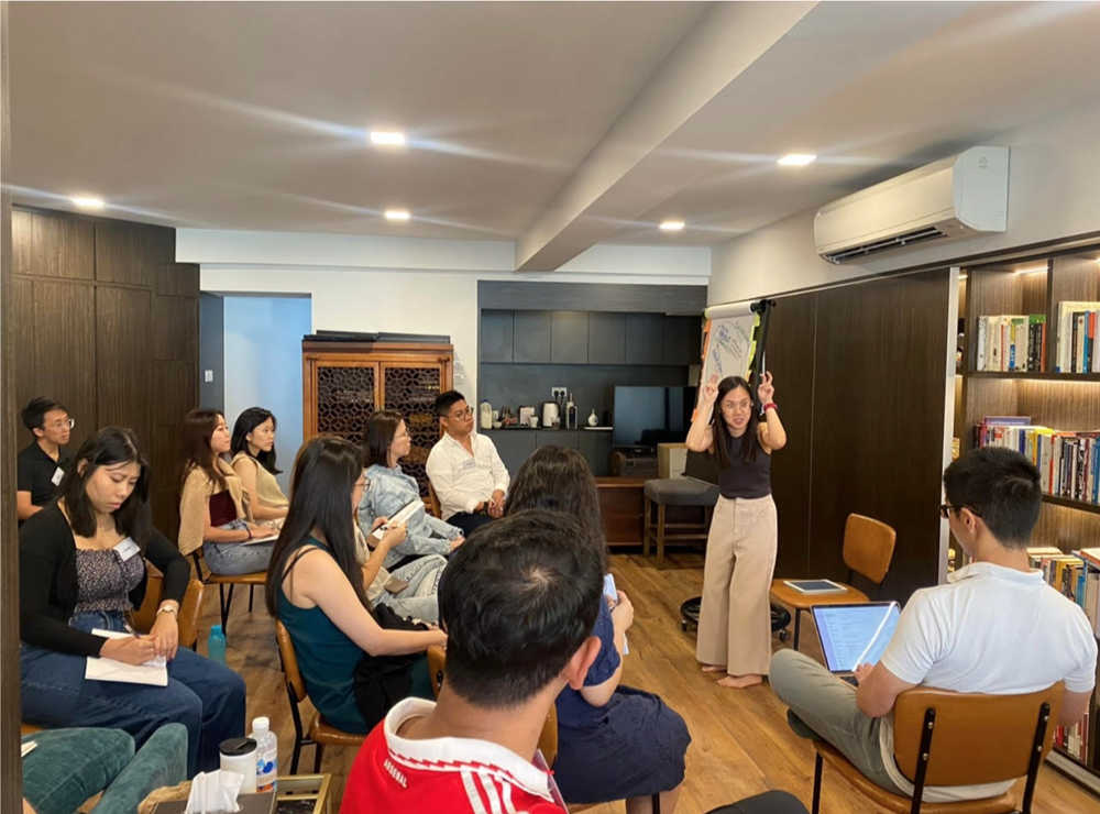 Group of people watching a woman presenting with a whiteboard in an office.