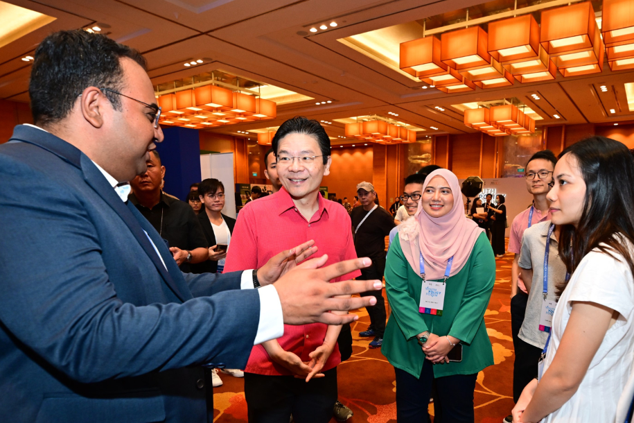 PM Wong standing in a circle with a few attendees. Everyone looks at a guy speaking.