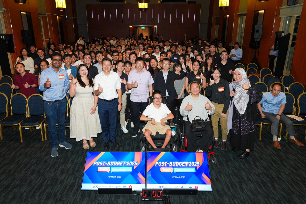 Large group at "Post-Budget 2025" event giving thumbs up