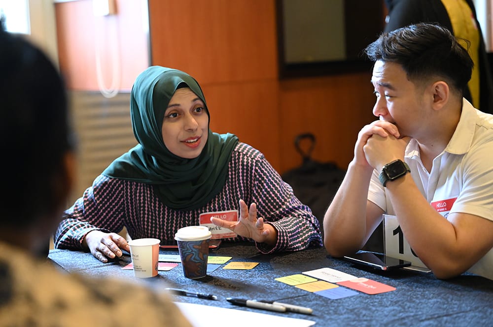 People at table with coffee cups, name tags, and cards in a group activity.
