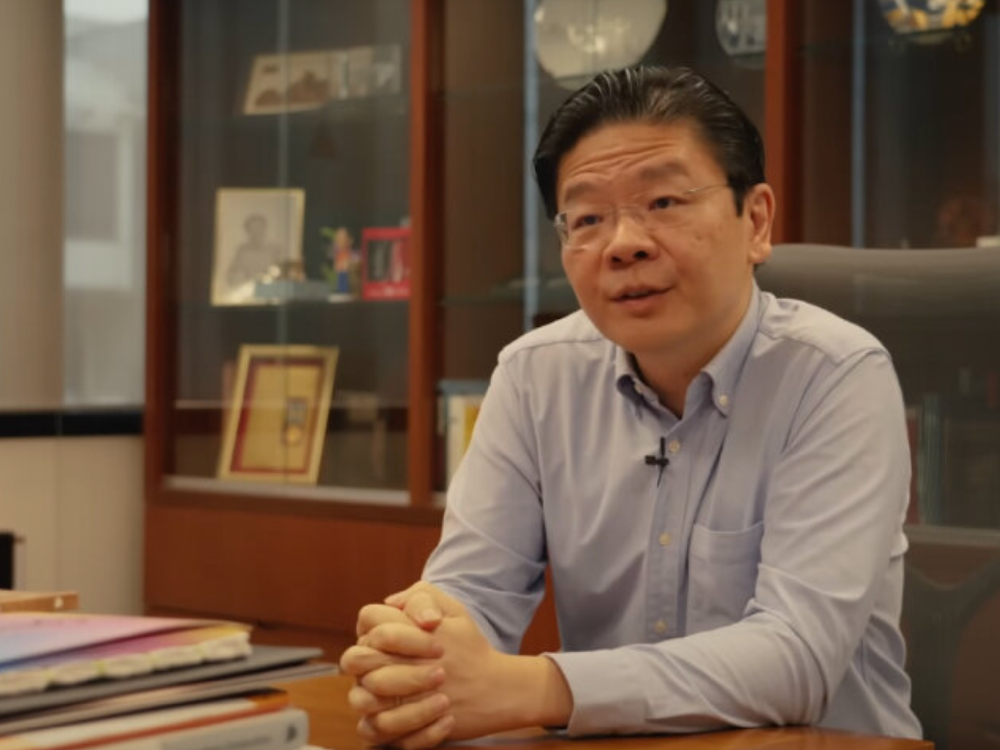 Lawrence Wong seated at a desk, speaking during an interview in his office setting