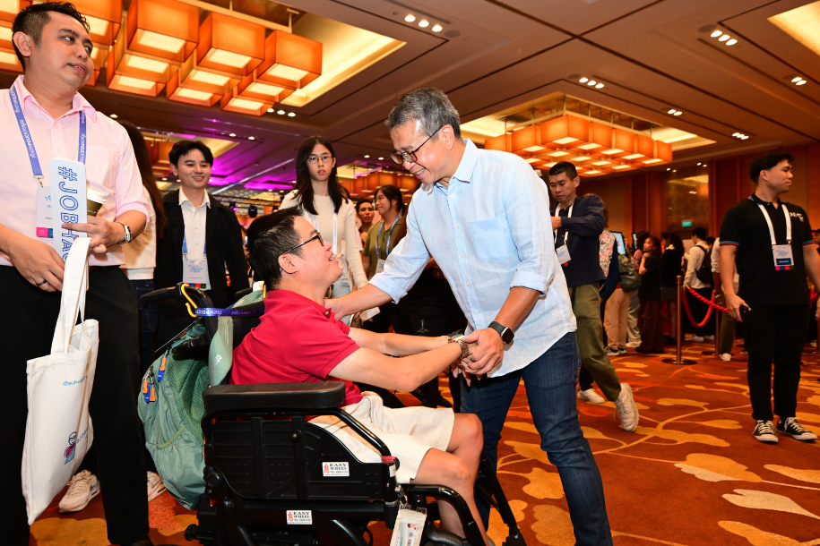 Minister Edwin Tong shaking the hands of a citizen in a wheelchair