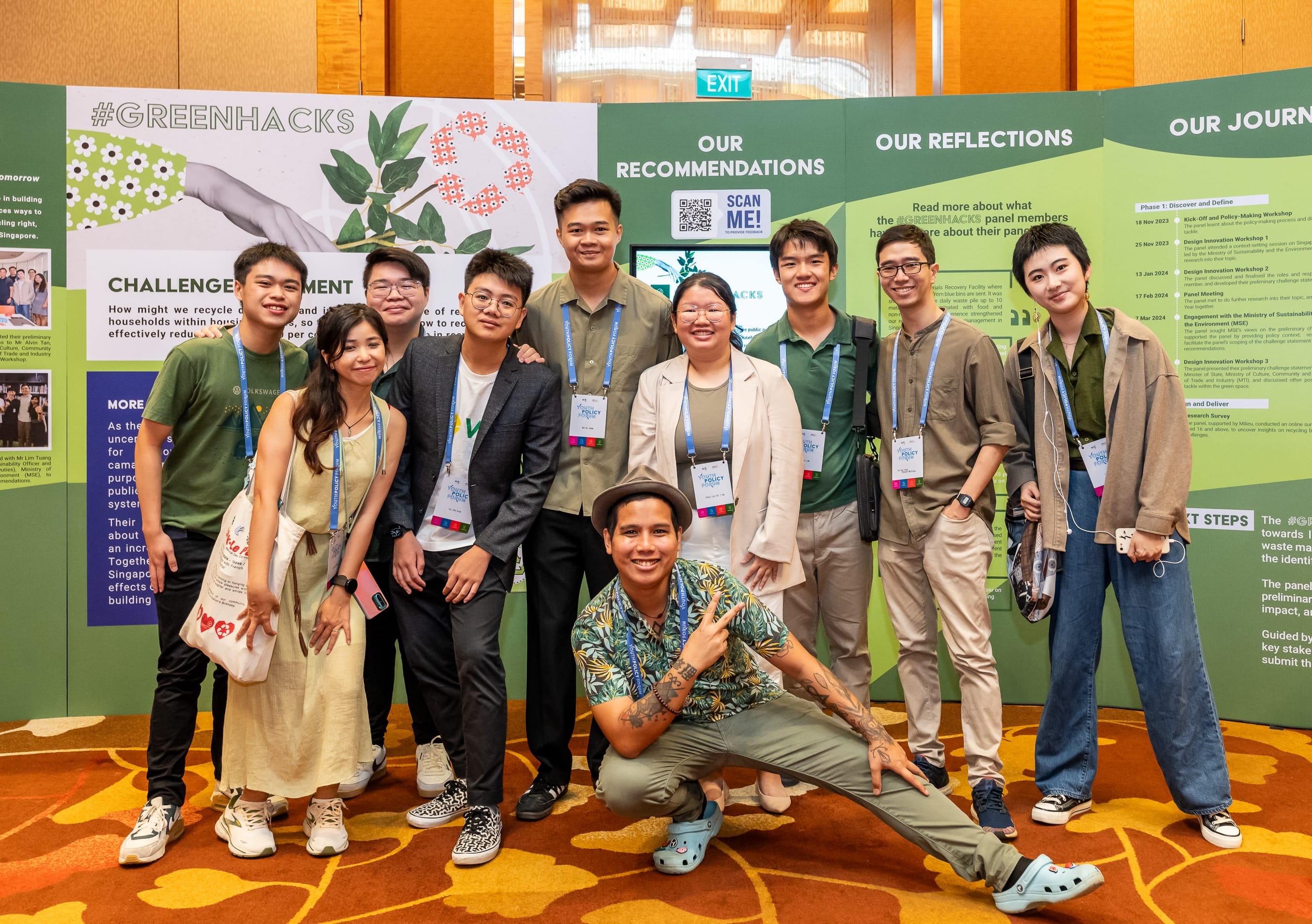 Group of people posing in front of a #GREENHACKS information display.
