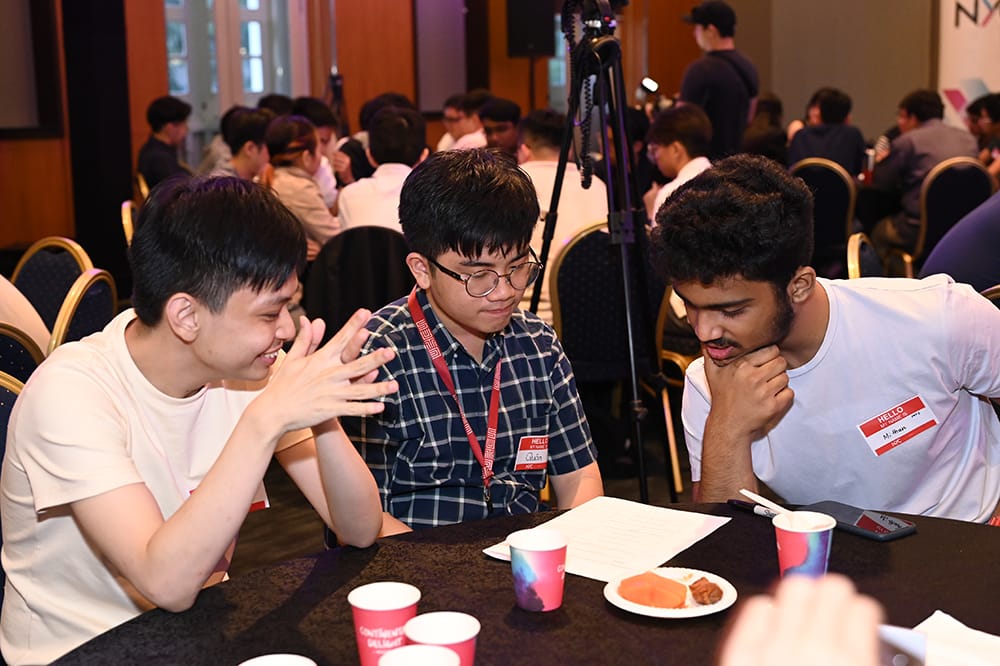 Three people collaborate at a table with snacks and Continental Delight cups.