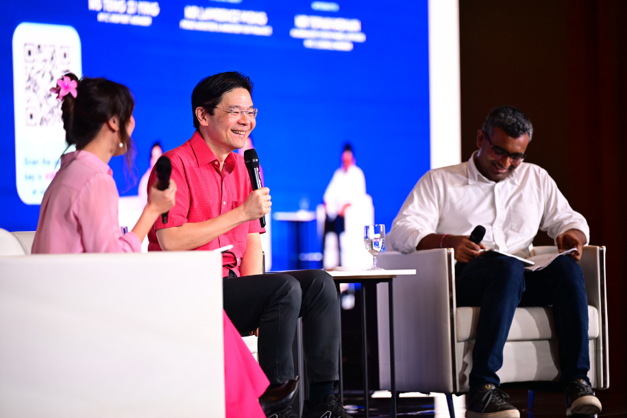 Prime Minister Wong having a dialogue session on stage with two other hosts.