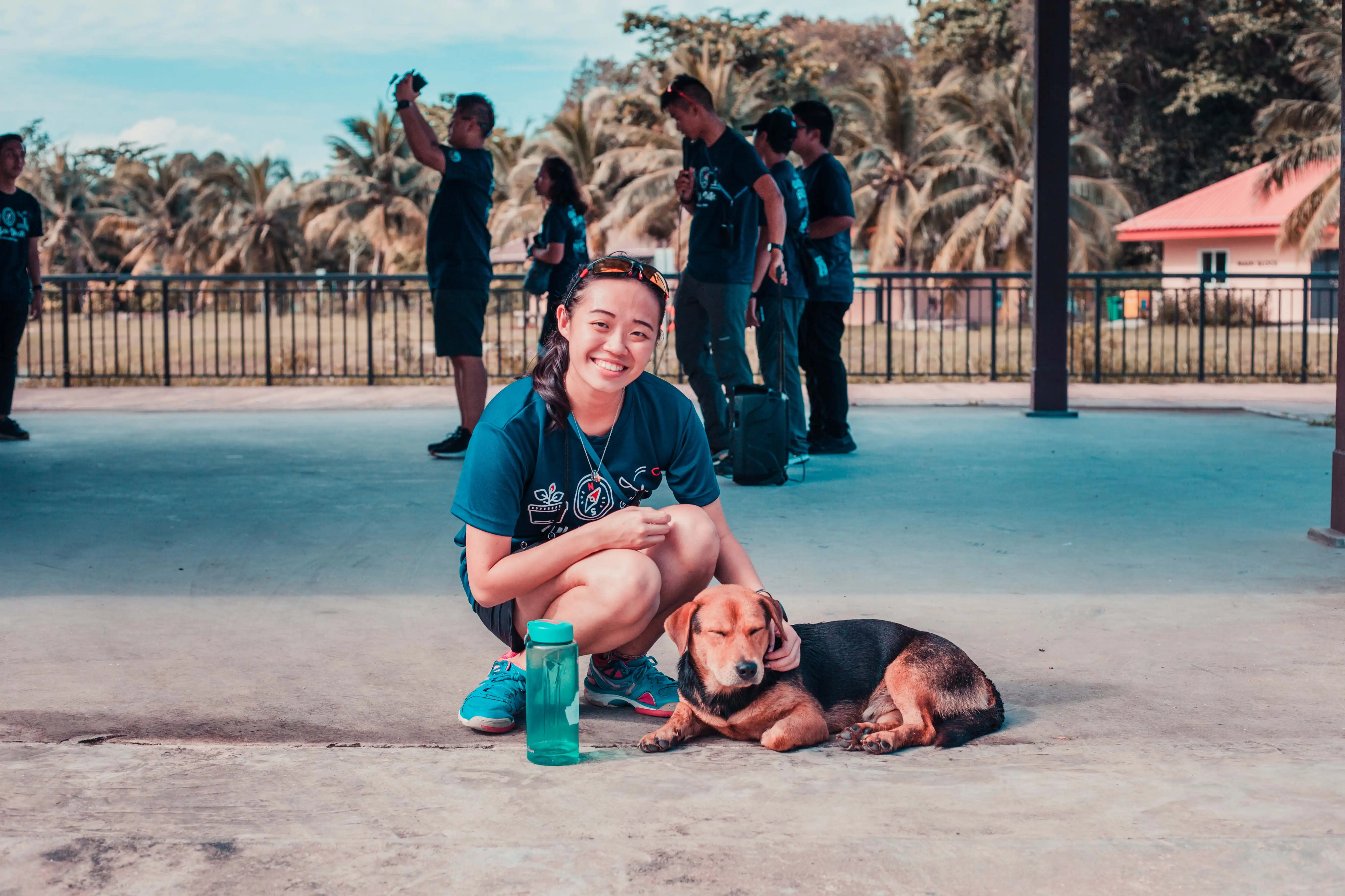 Smiling participant kneels beside a dog while others gathered in the background.