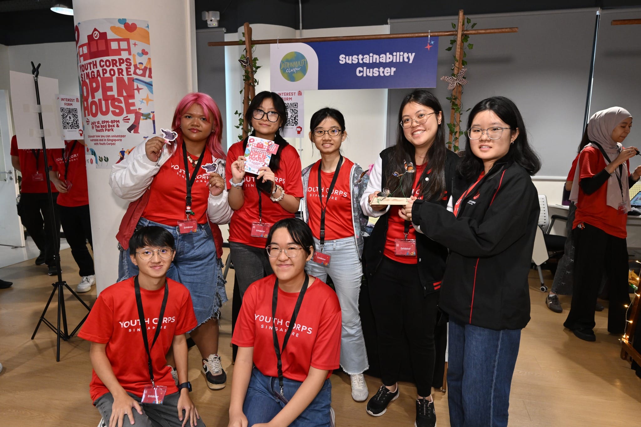 Group in Youth Corps Singapore shirts at a "Sustainability Cluster" open house event.