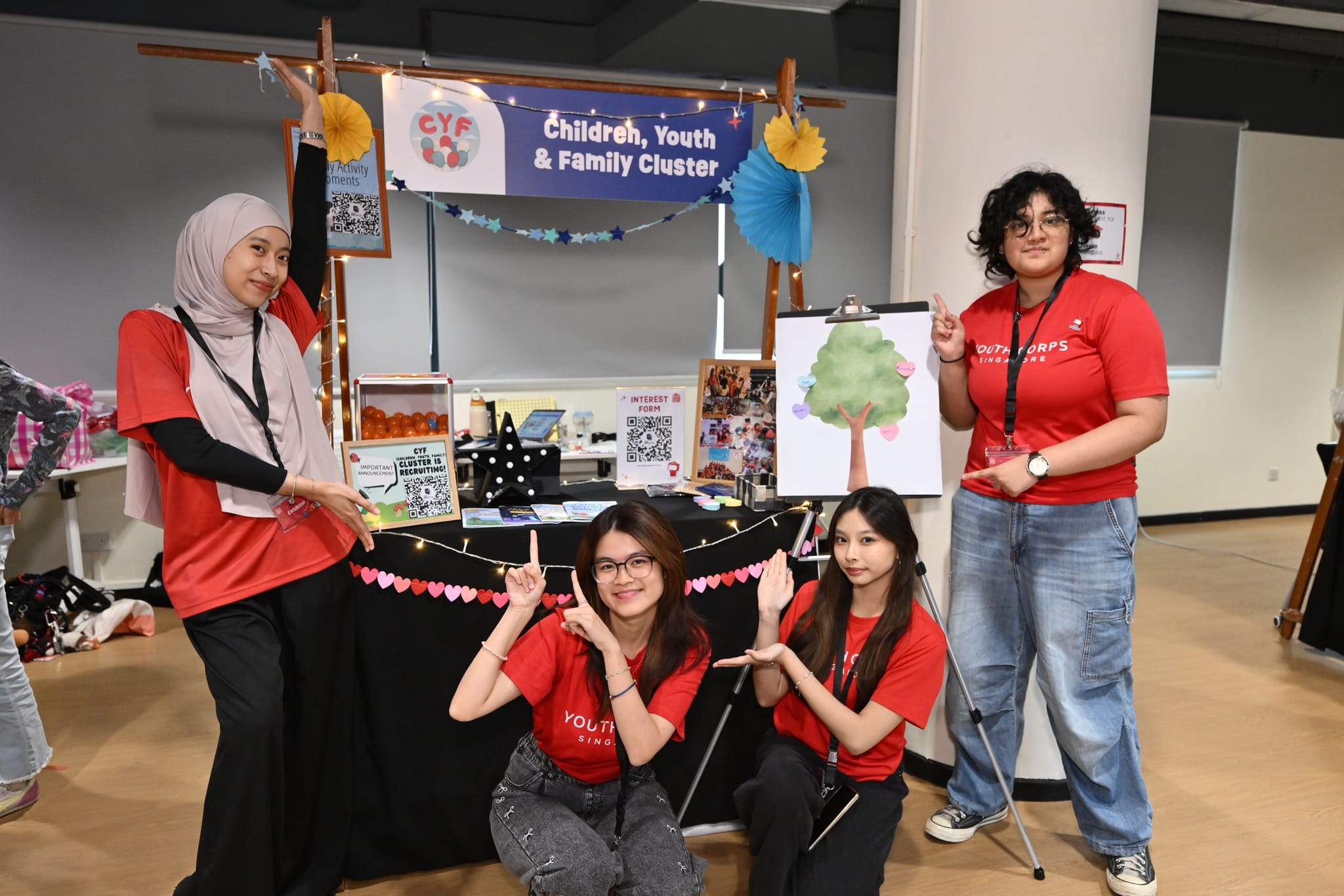 Four Youth Corps Singapore volunteers pose at a CYF recruitment booth.