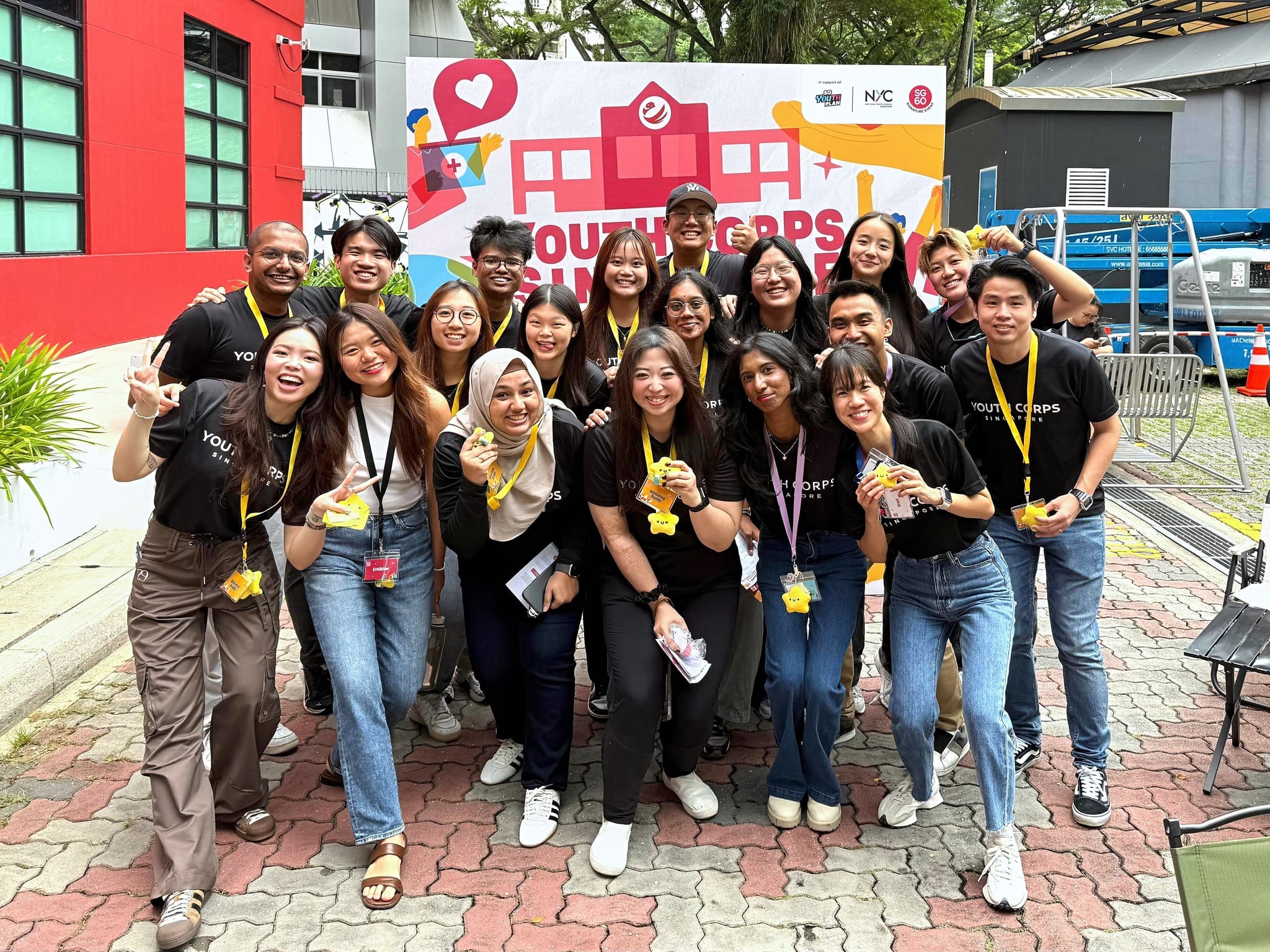 Group of people posing in front of a Youth Corps Singapore banner.