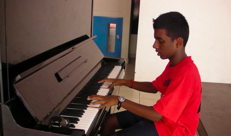 Boy in red shirt playing the piano