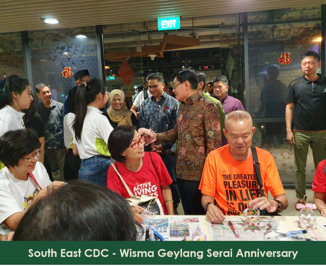 Group of people gathered around tables, some crafting, others observing.