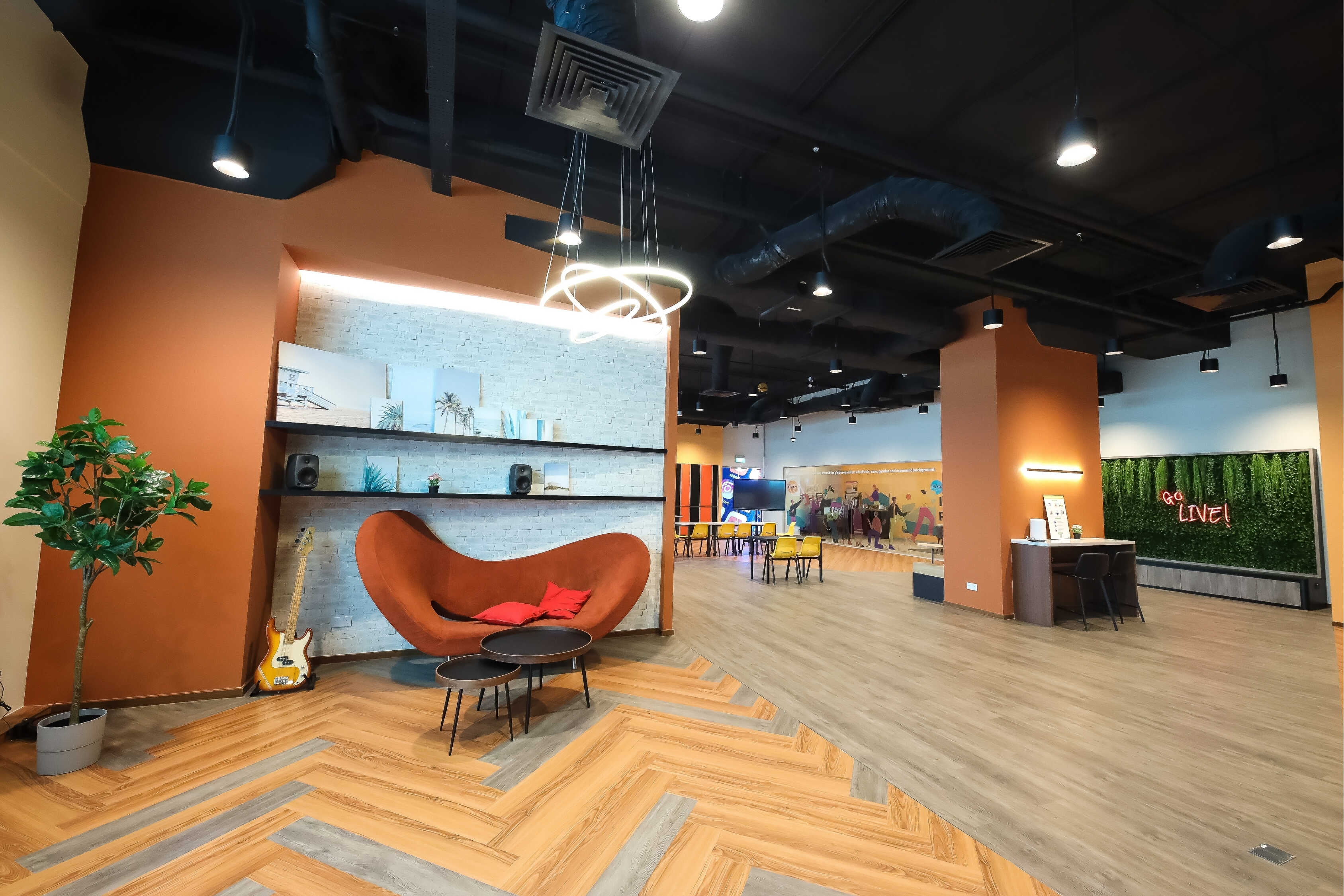 Lobby area with orange sofa, round tables, guitar, and shelves with pictures on the wall.
