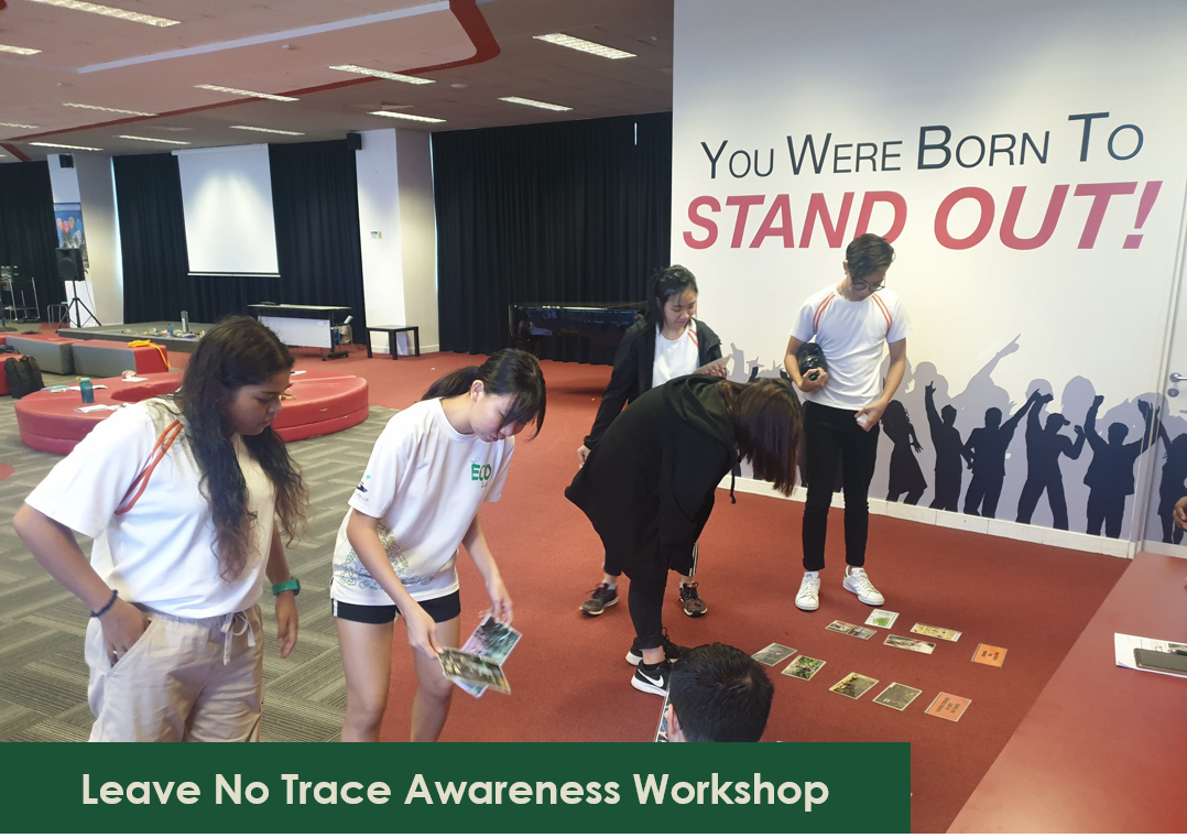 Attendees review cards on floor at 'Leave No Trace Awareness Workshop', mural reads 'You Were Born To STAND OUT!'