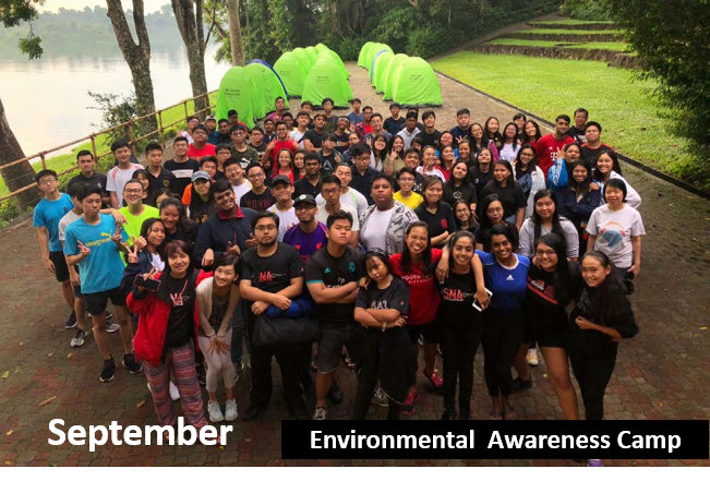 Group of people, outdoors, by tents, near water. 'Environmental Awareness Camp' text shown.