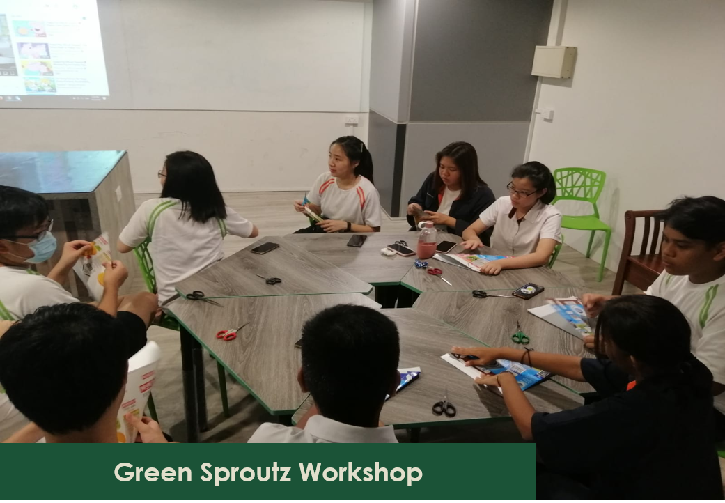 Students at a workshop sitting around a table with scissors and art supplies.