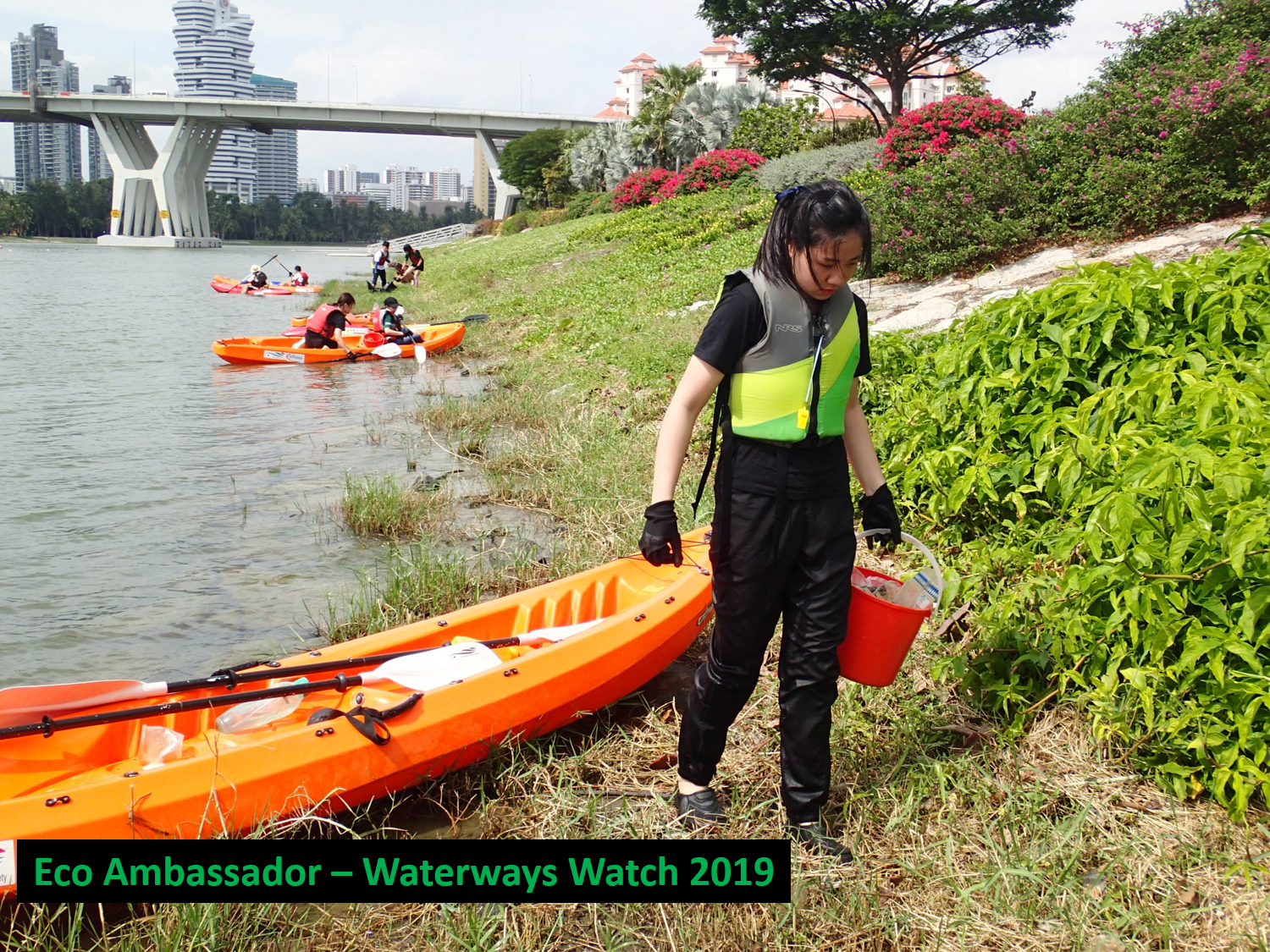 Waterways cleanup: person in life vest with bucket, orange kayak, kayakers, and bridge.