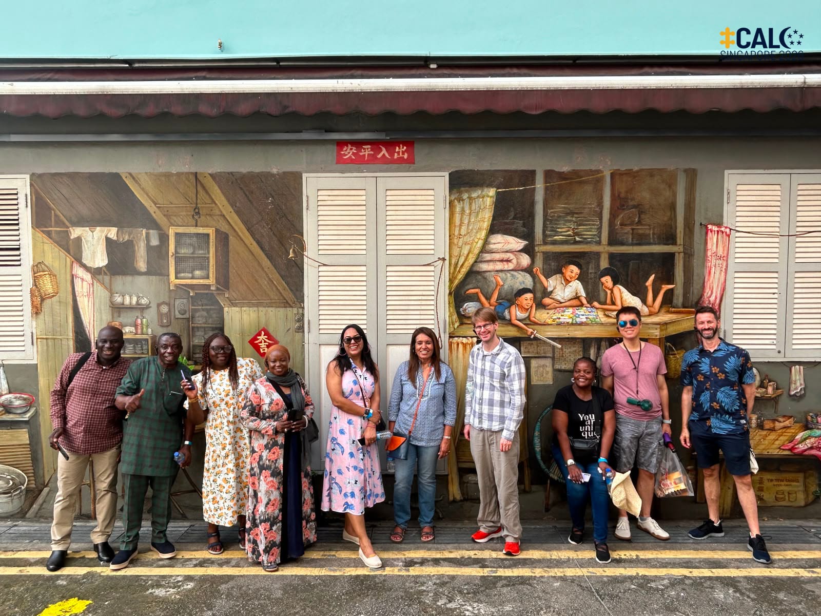 Conference delegates pose for a photo in front of a shophouse mural in Chinatown, Singapore, on 18 July 2026.