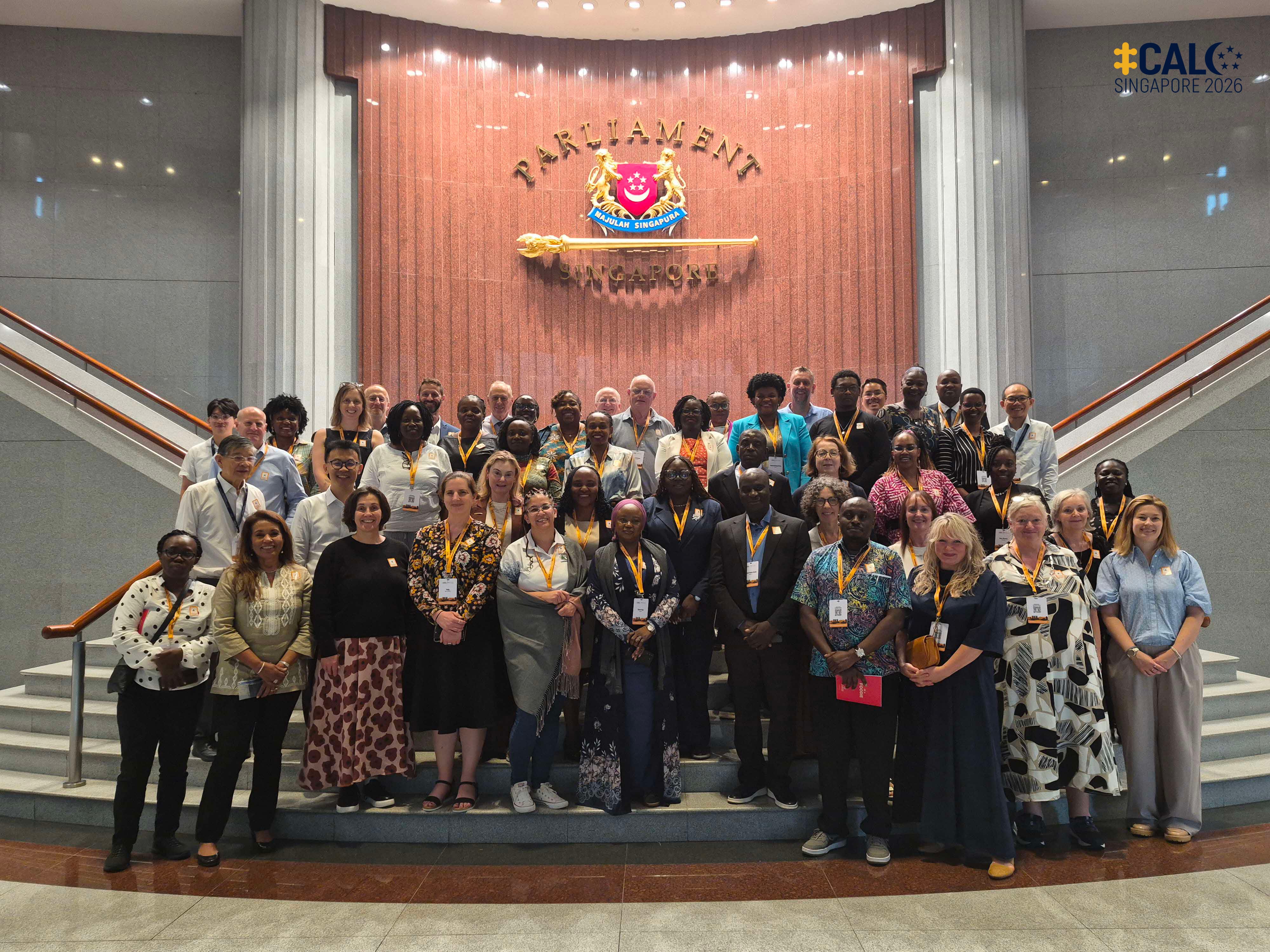 Conference delegates pose for a group photo at a staircase in front of the symbol of Parliament during a visit to Parliament House, Singapore, on 17 July 2026.