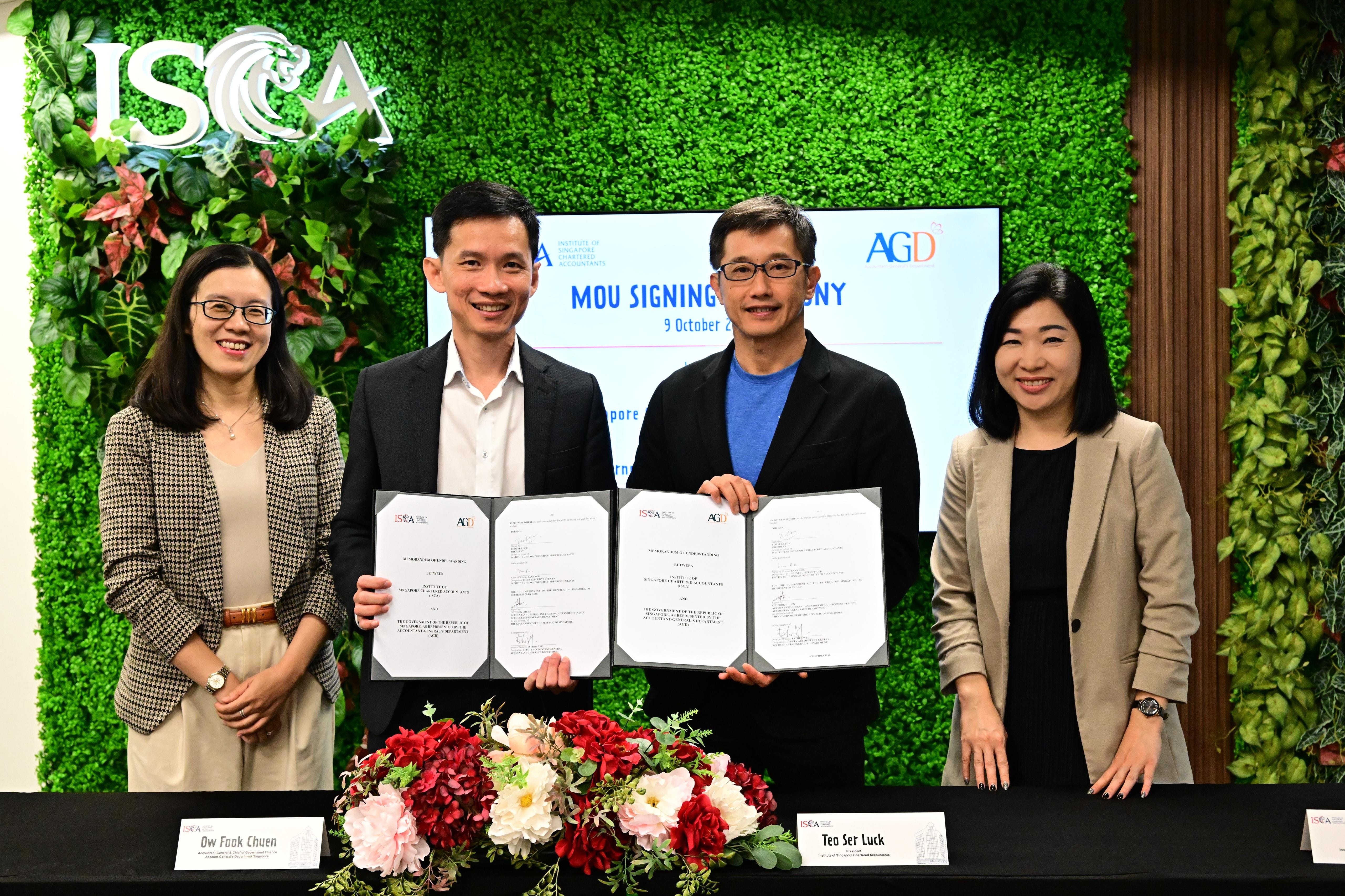 Four people holding ISCA & AGD documents, floral arrangement, backdrops with foliage & logo.