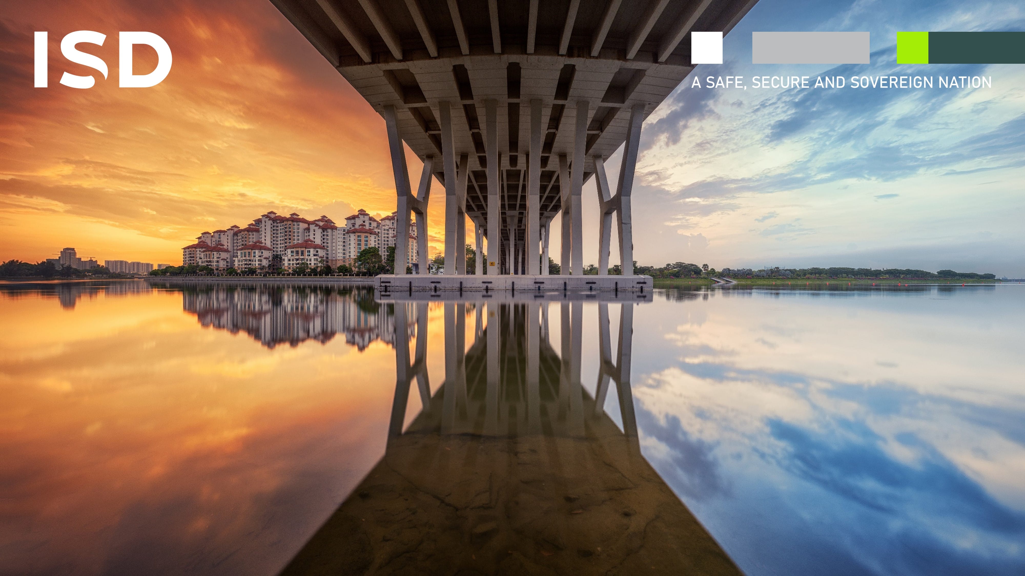 Reflection of buildings and a bridge's pillars on calm water during sunset.