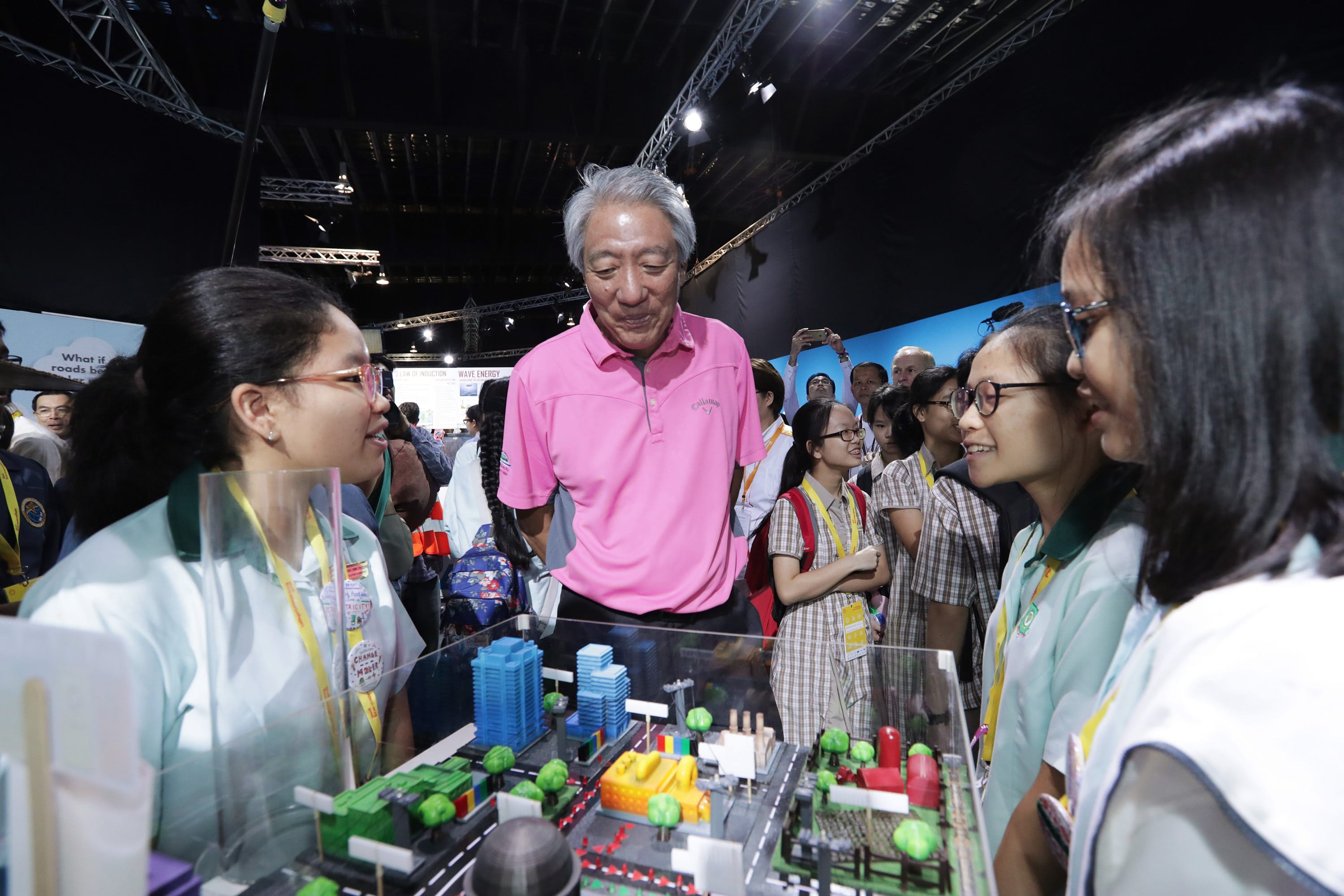 People viewing city model with buildings and roads. One man wears a pink Callaway polo shirt.