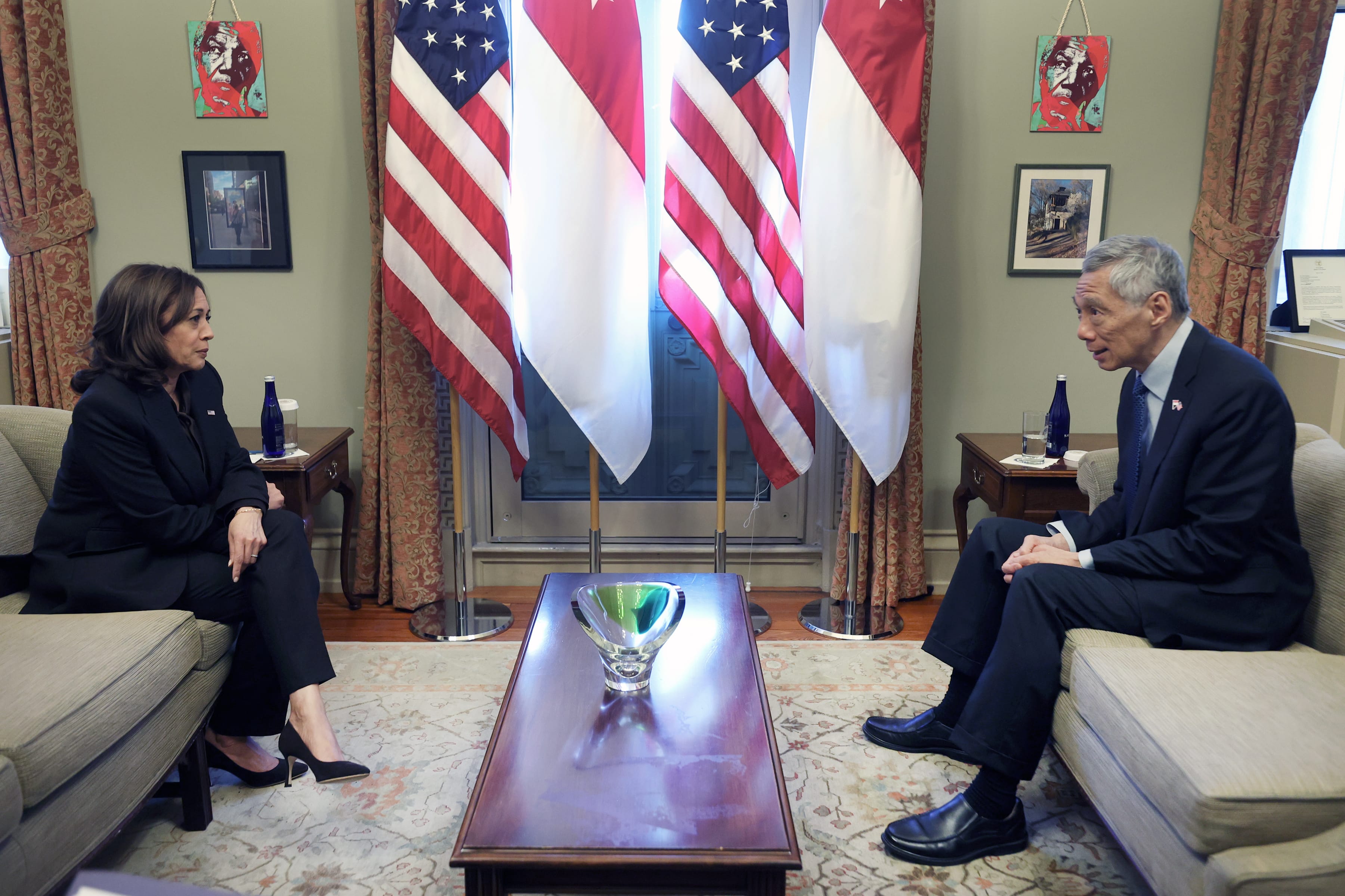 Kamala Harris and Lee Hsien Loong sit on couches, facing each other with flags behind them.