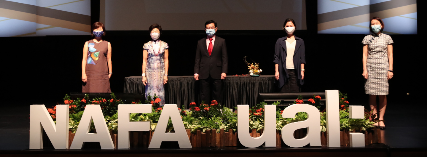 Five masked individuals stand on a stage behind NAFA ual letters and flower displays.