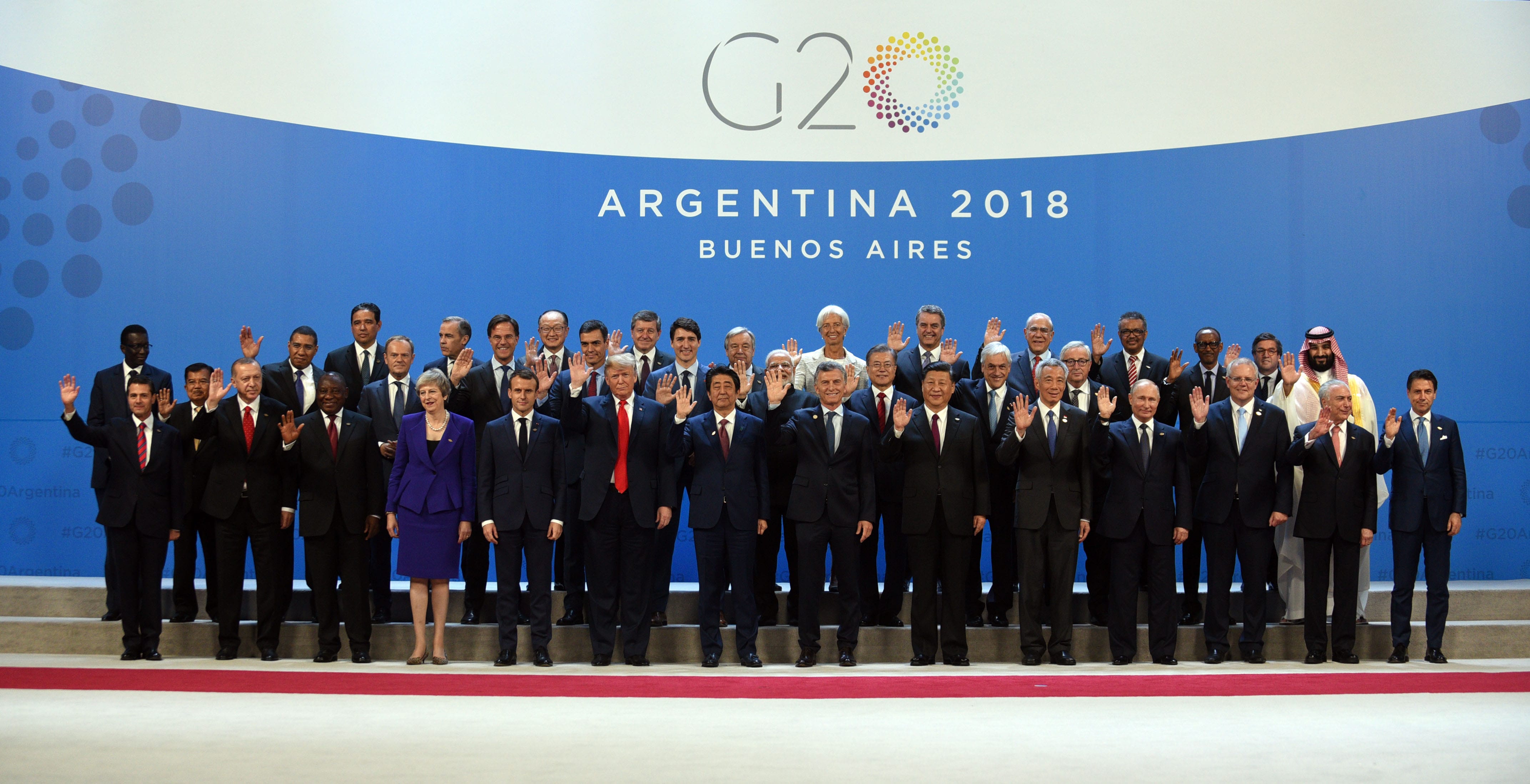 Group portrait: G20 leaders at Argentina 2018 Buenos Aires summit, waving with hands raised.