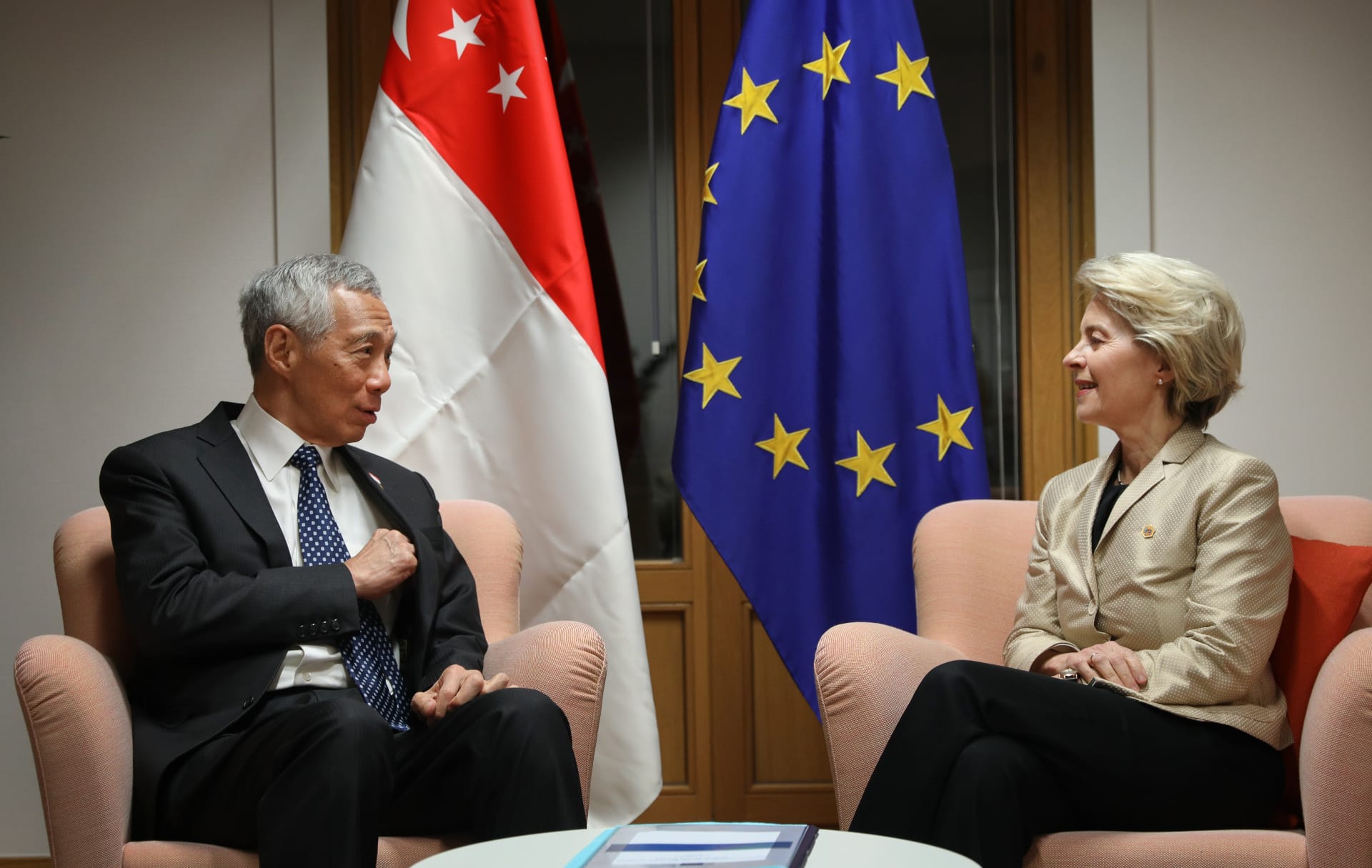 Ursula von der Leyen and Lee Hsien Loong sit, with Singapore and EU flags behind.
