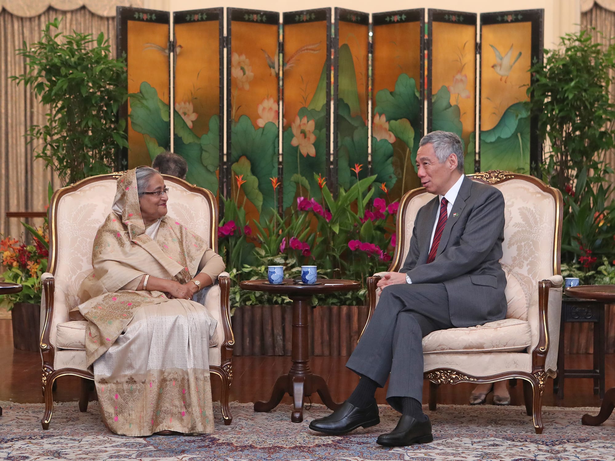 Lee Hsien Loong and Sheikh Hasina seated in ornate chairs facing each other, with a folding screen behind.