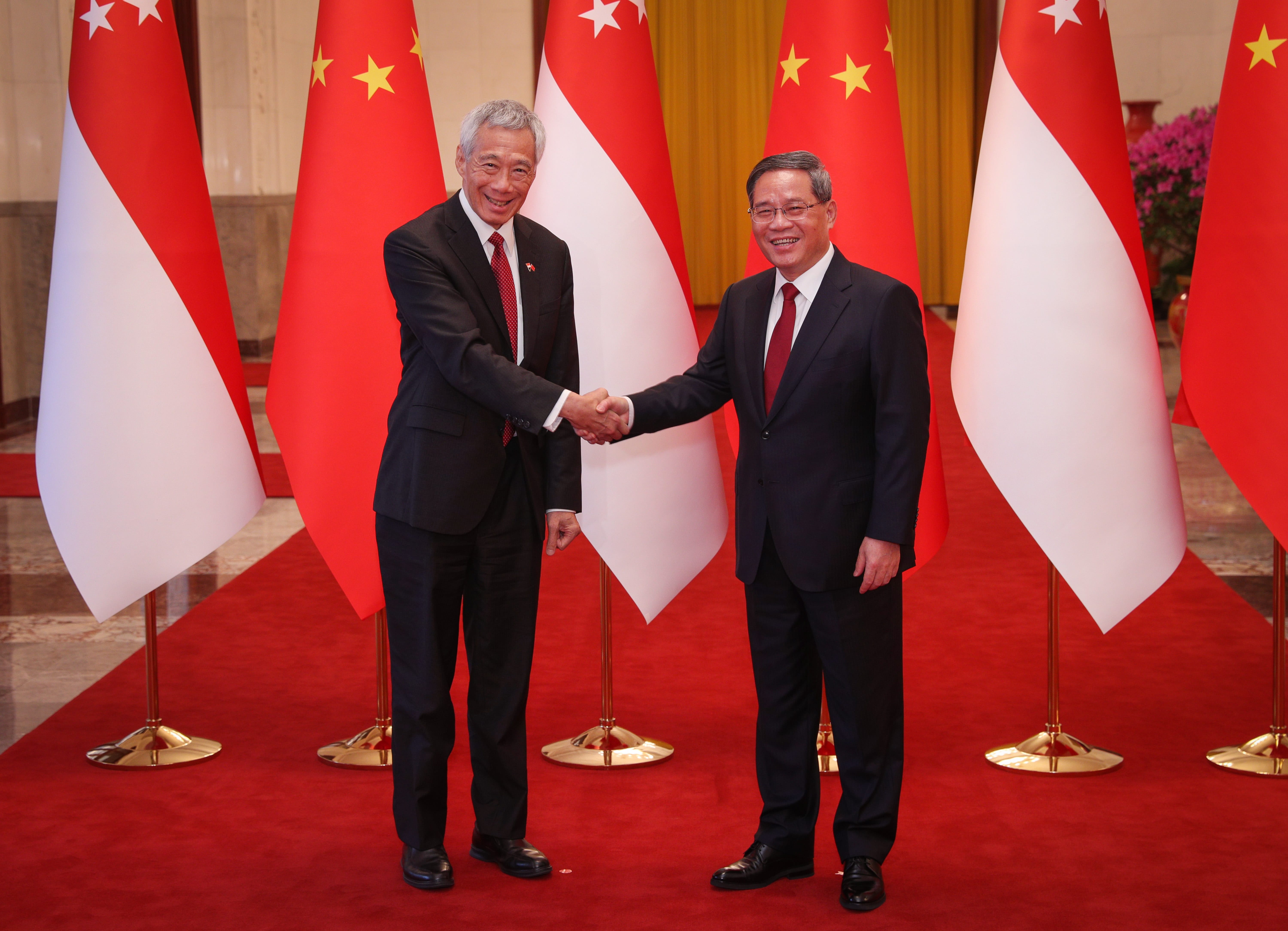 Lee Hsien Loong shakes hands with an official, flags of China and Singapore in background.