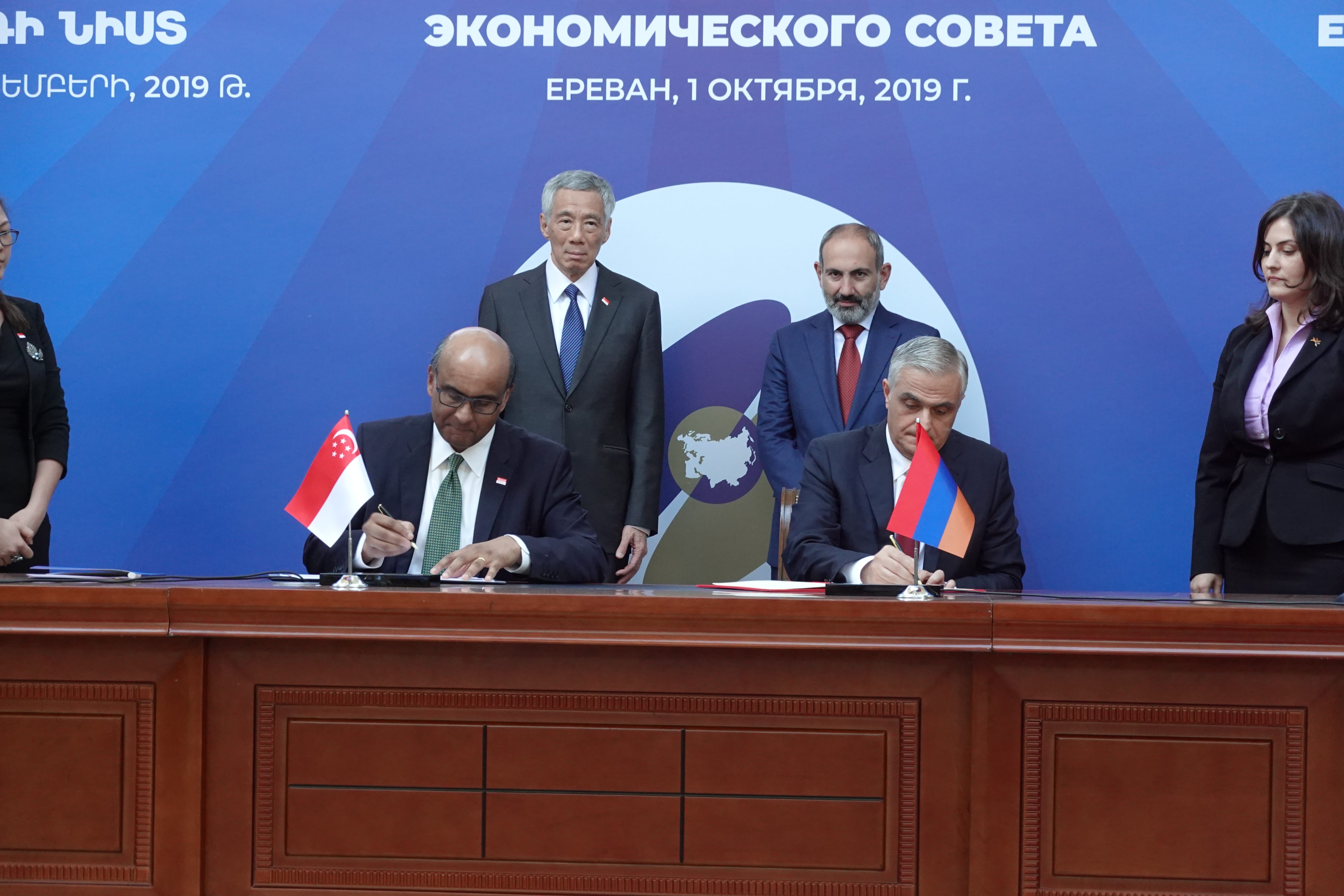 Signing at table with Singapore and Armenian flags. Halimah Yacob, Nikol Pashinyan behind.