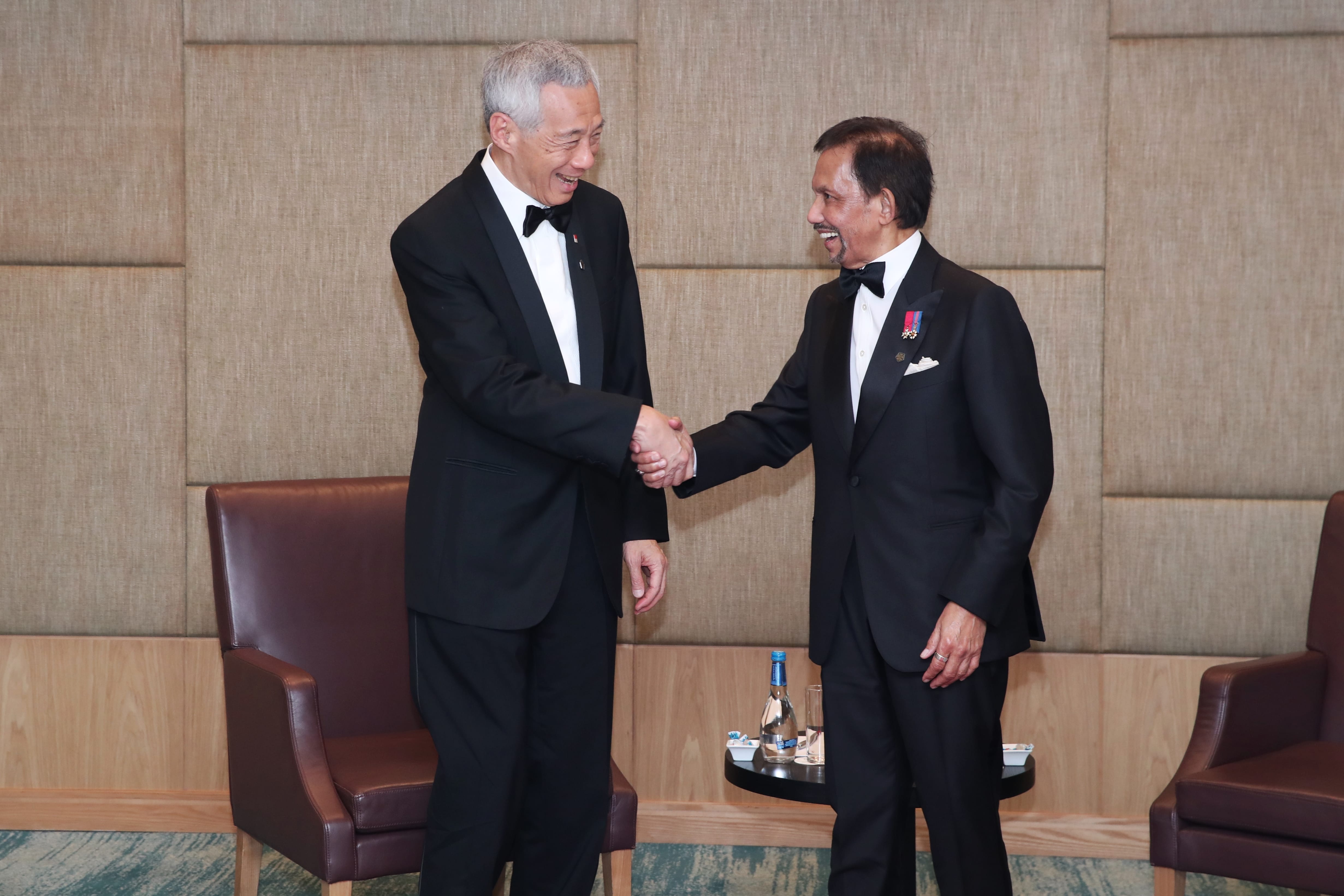 Lee Hsien Loong and Hassanal Bolkiah in tuxedos shaking hands.