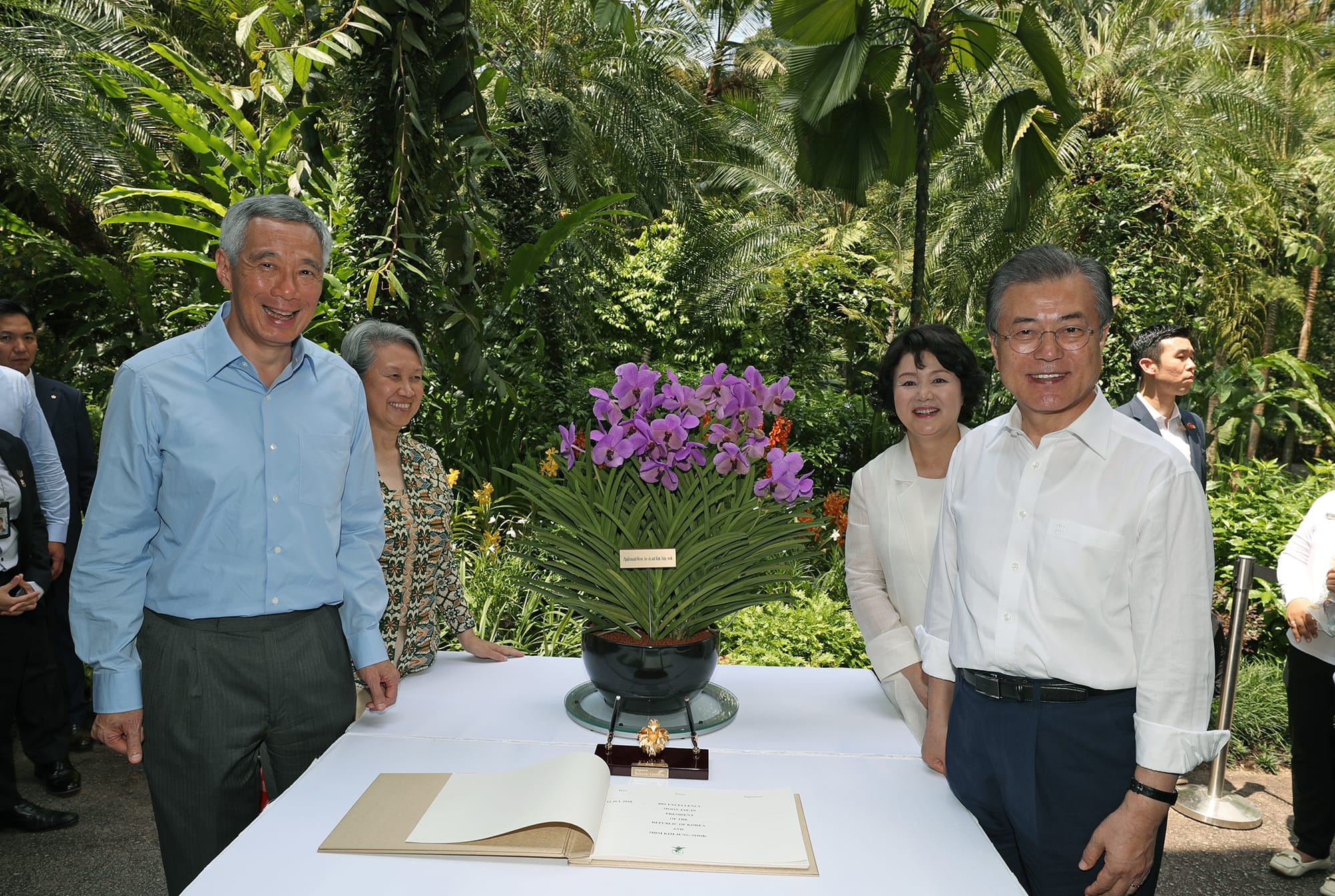 Lee Hsien Loong and Moon Jae-in near a table with an orchid arrangement and a guestbook.