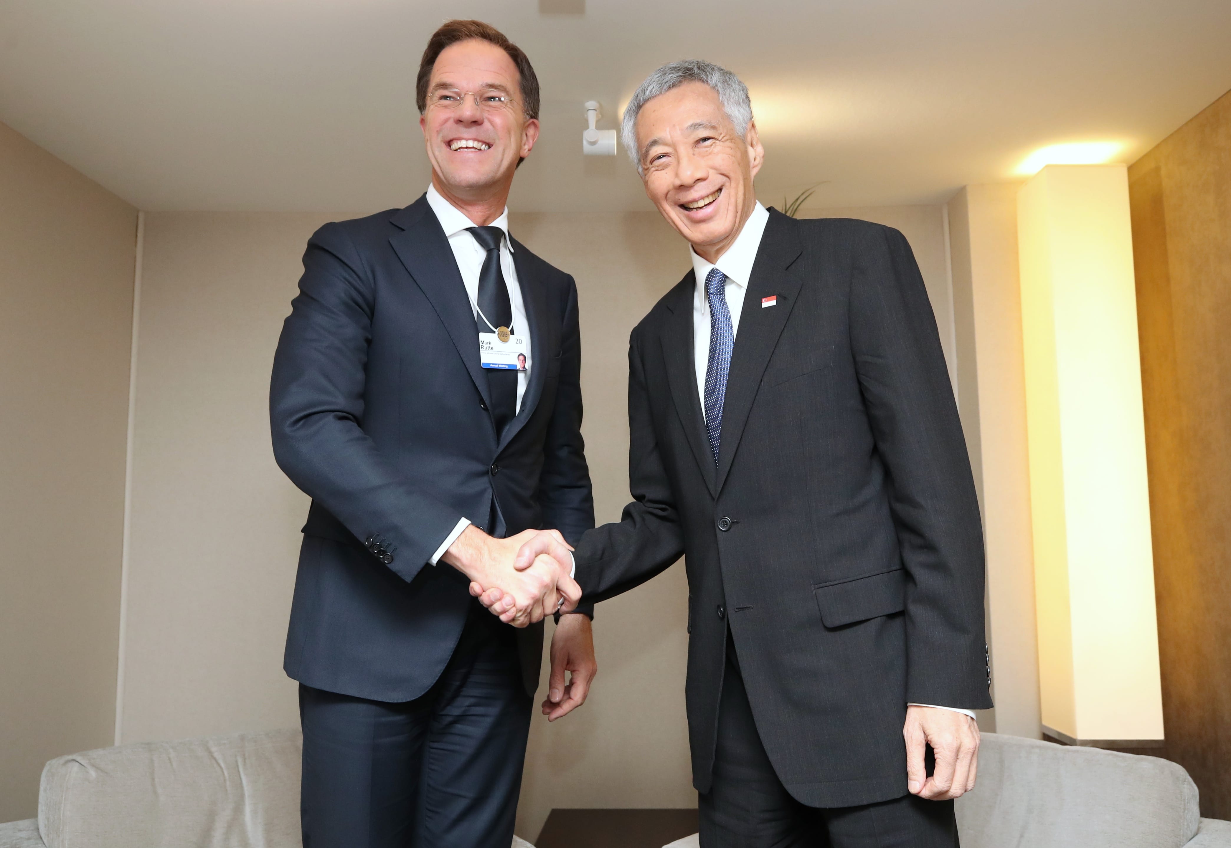 Mark Rutte and Lee Hsien Loong shake hands, both in dark suits, smiling.